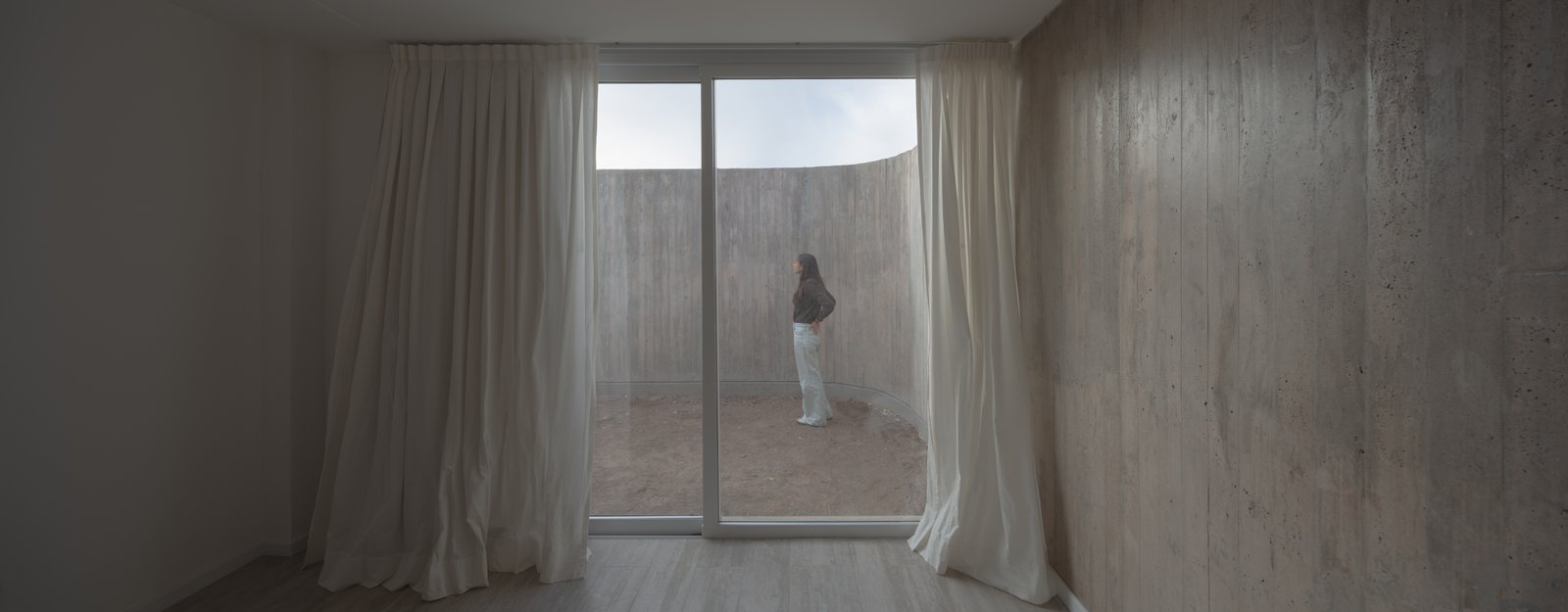 Interior moderno con patio curvo y cortinas blancas — proyecto Vivienda CCE, por ONA - Oficina Nómada de Arquitectura, en M5505 Chacras de Coria