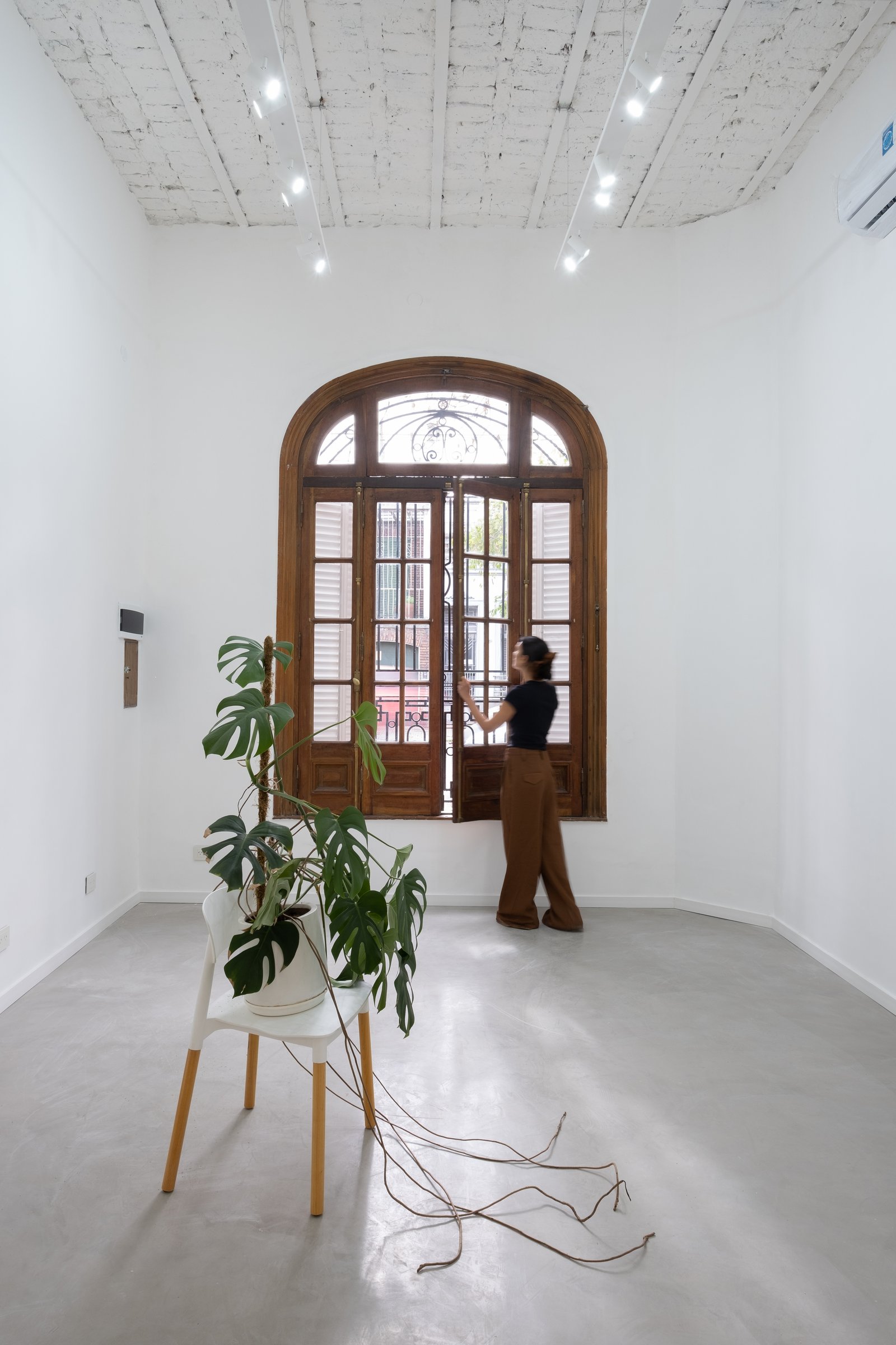 Espacio interior minimalista con gran ventana arqueada de madera — proyecto Casa Patio, por Herrera Ungaro, en San Cristóbal