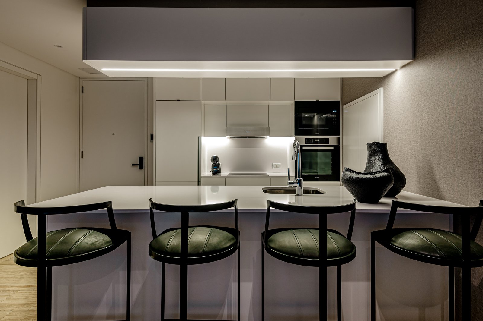 Cocina moderna minimalista con isla de mármol y banquetas verdes — proyecto OBRA OCEANA, PUERTO MADERO, por MARCELO MAZZA, en Puerto Madero