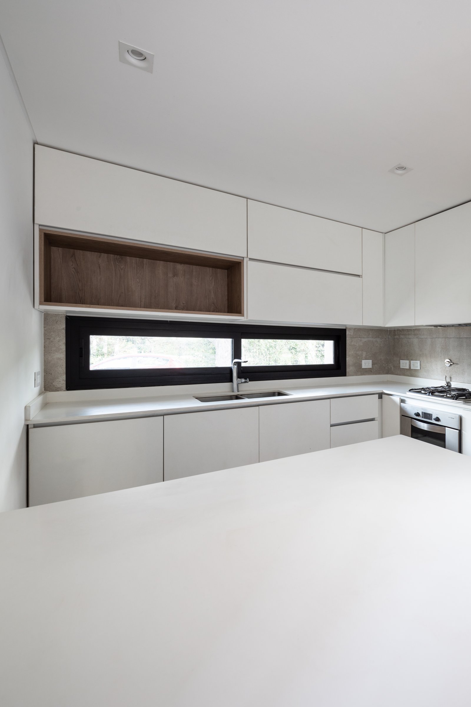 Cocina moderna minimalista con muebles blancos y ventana panorámica — proyecto Casa Emilia, por Grupo CRBN, en Parque Leloir