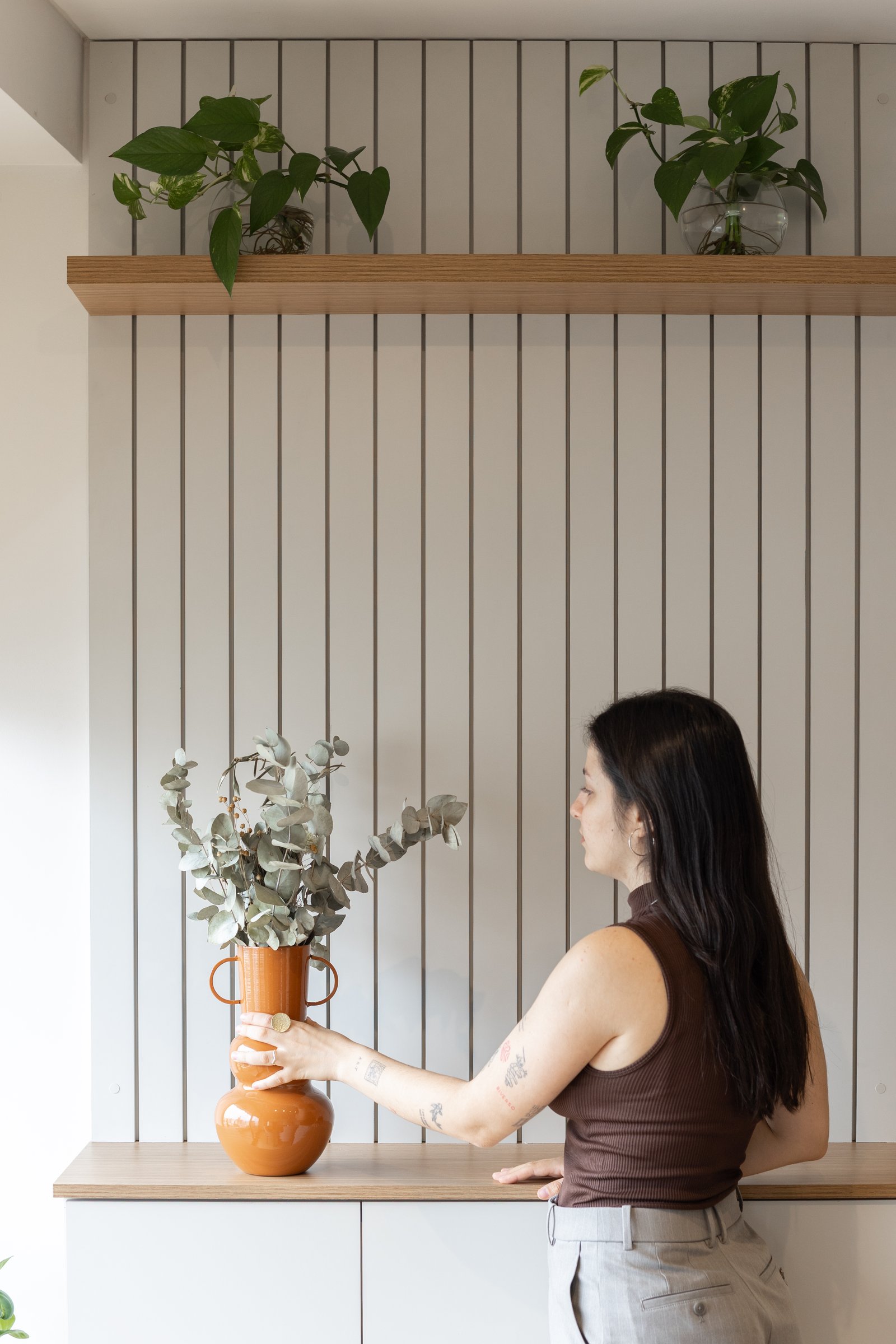 pared de listones de madera y estantes flotantes con plantas y jarrón — proyecto Rio, por Martina Kleinert, en Saavedra