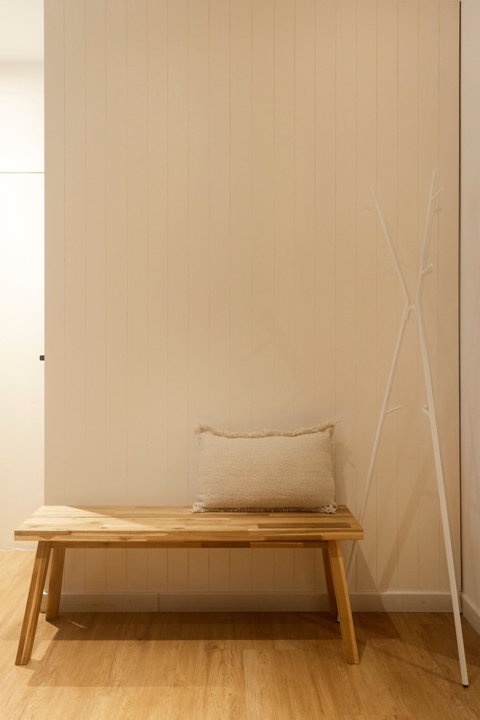 corredor minimalista com banco de madeira e detalhes decorativos — projeto REFORMA NE, por Rastro Estudio, em Palermo