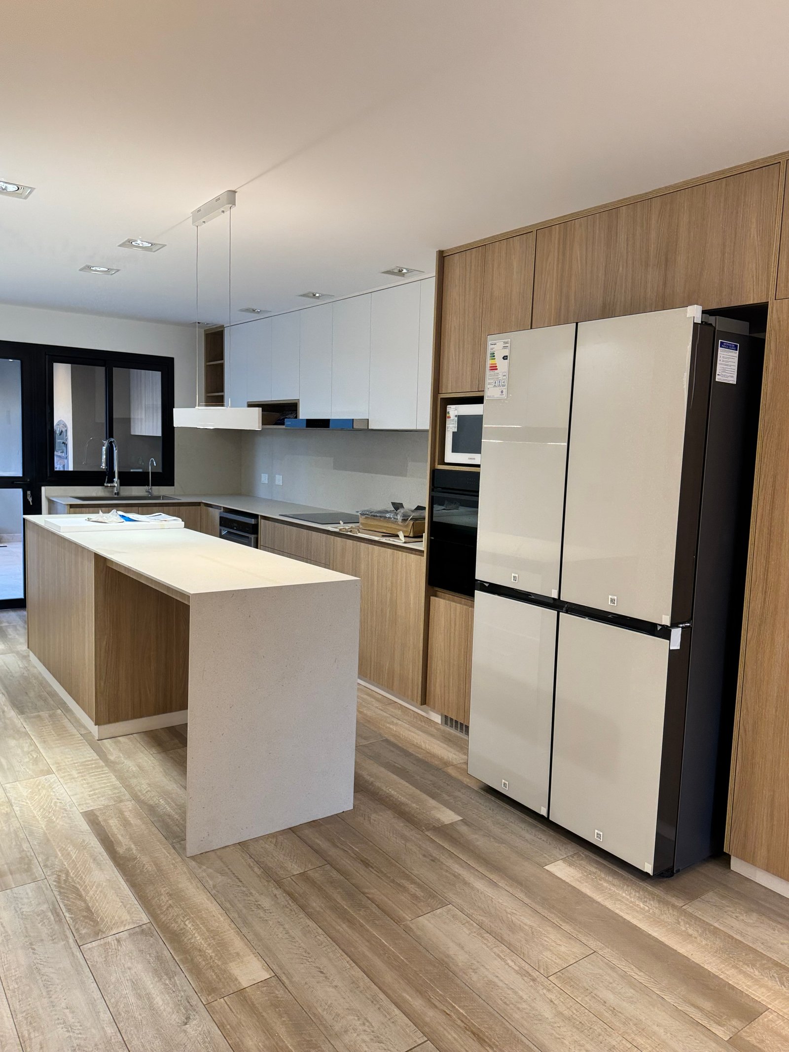 Cozinha moderna, ilha branca, madeira natural, estilo minimalista — projeto CASA LEAN, por Estudio Grupo 32, em Vicente López