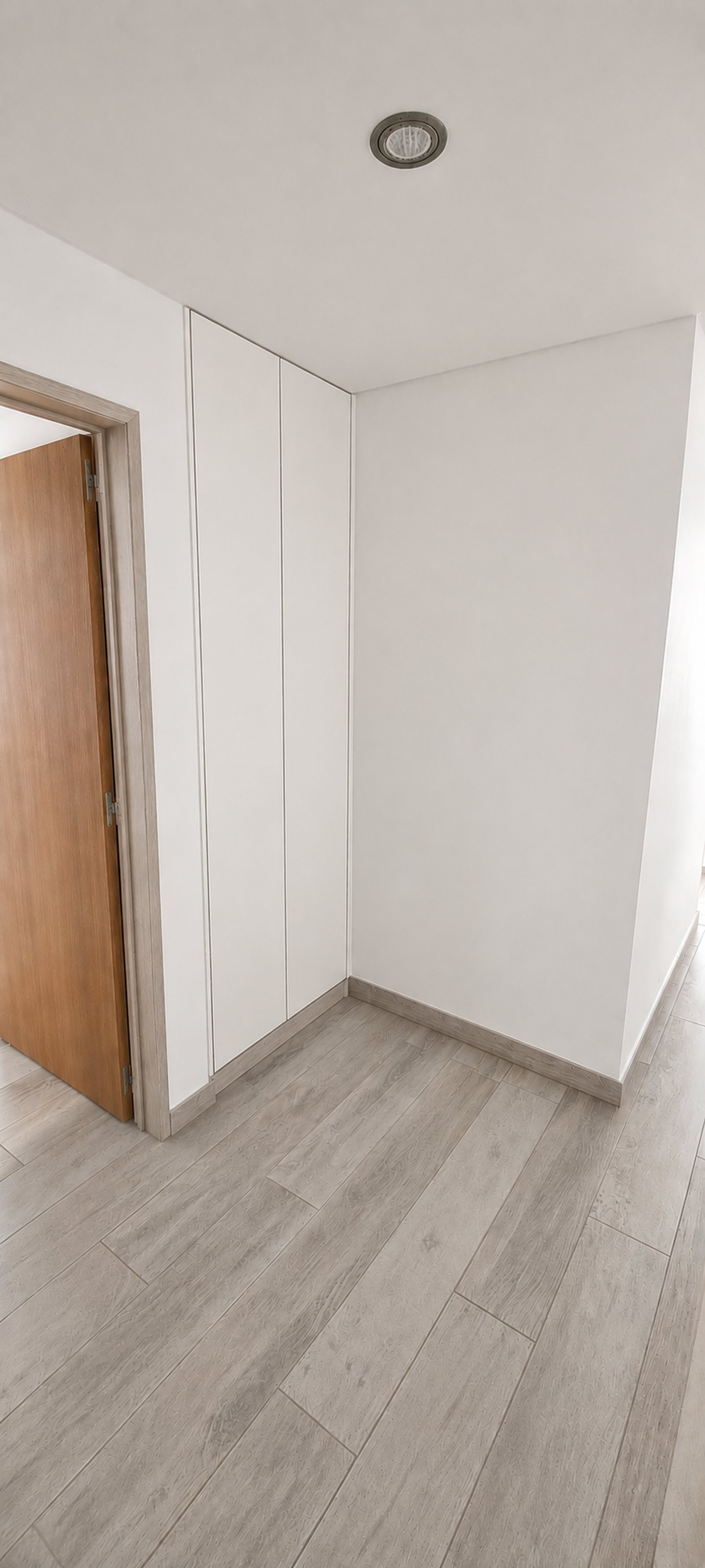 Pasillo moderno con piso de madera gris y armarios blancos empotrados — proyecto Interiorismo MyM, por Plasma co, en Lomas de Zamora