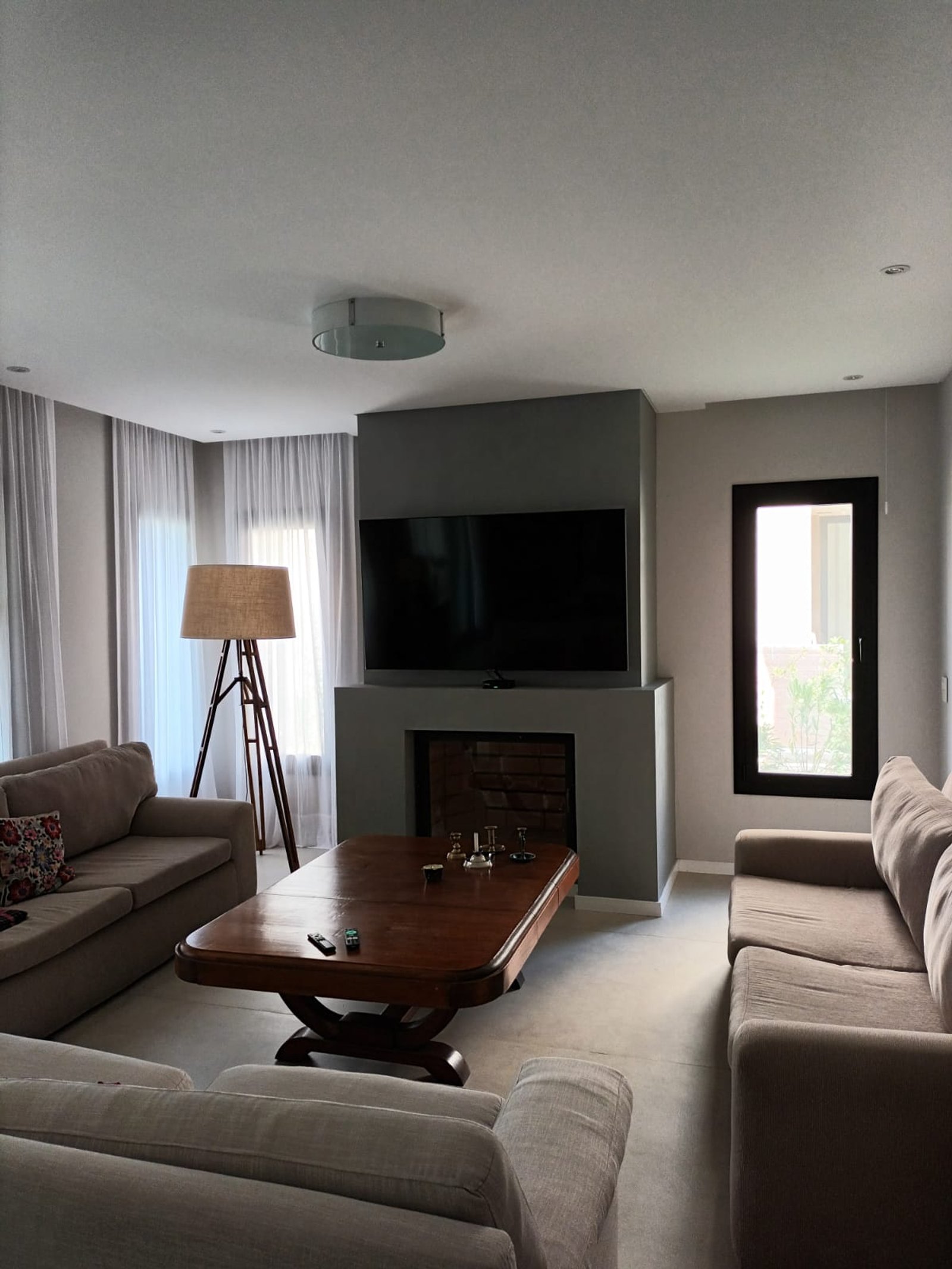 Sala de estar moderna com lareira cinza, sofás bege e luminária tripé — projeto CASA AL120, por DIB OBRIST Arquitectas, em Av. Jorge Newbery 8800
