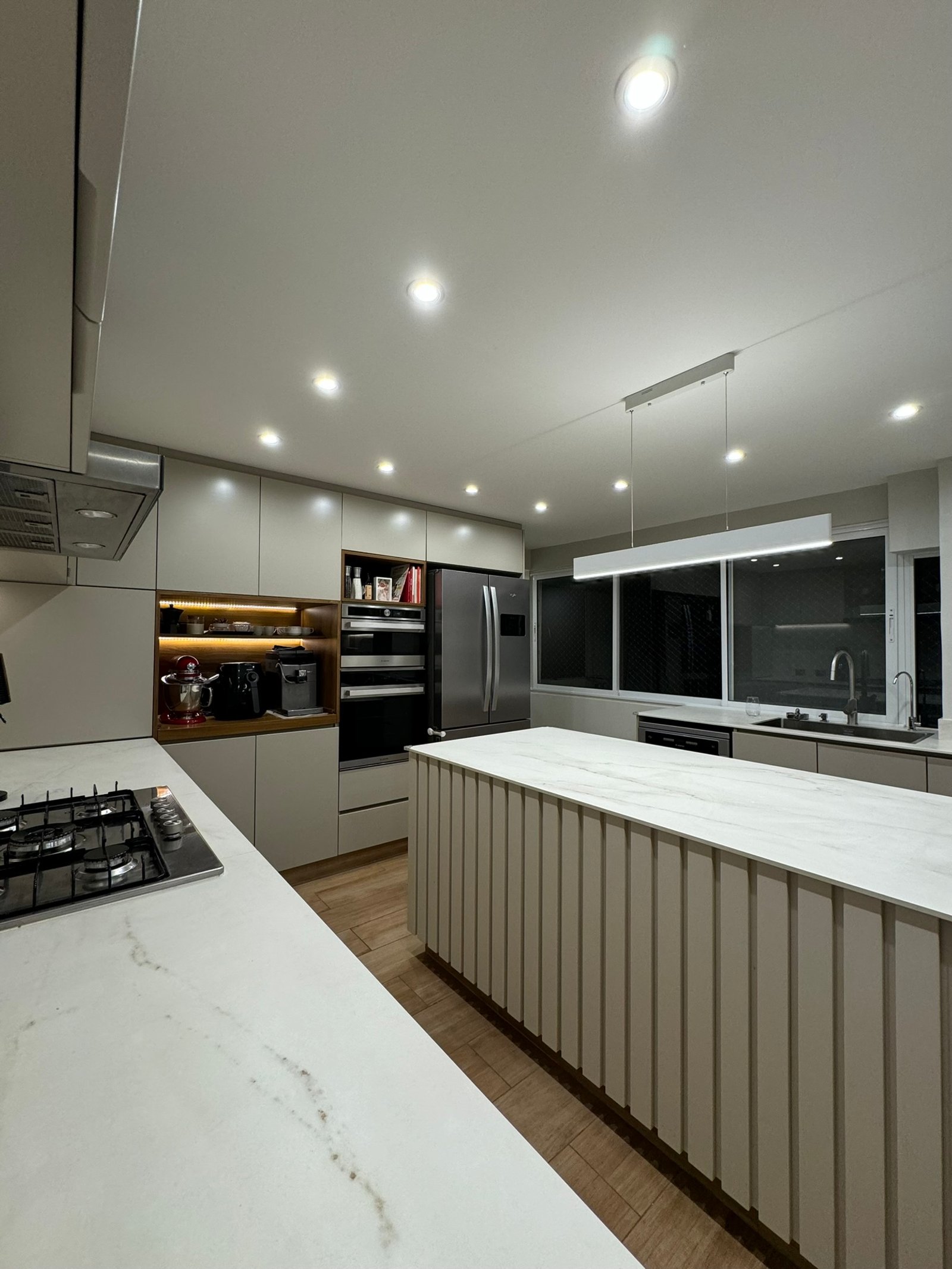 Cocina moderna minimalista con isla alargada y revestimiento acanalado — proyecto Las Heras, por MDBK Arquitectura, en Palermo