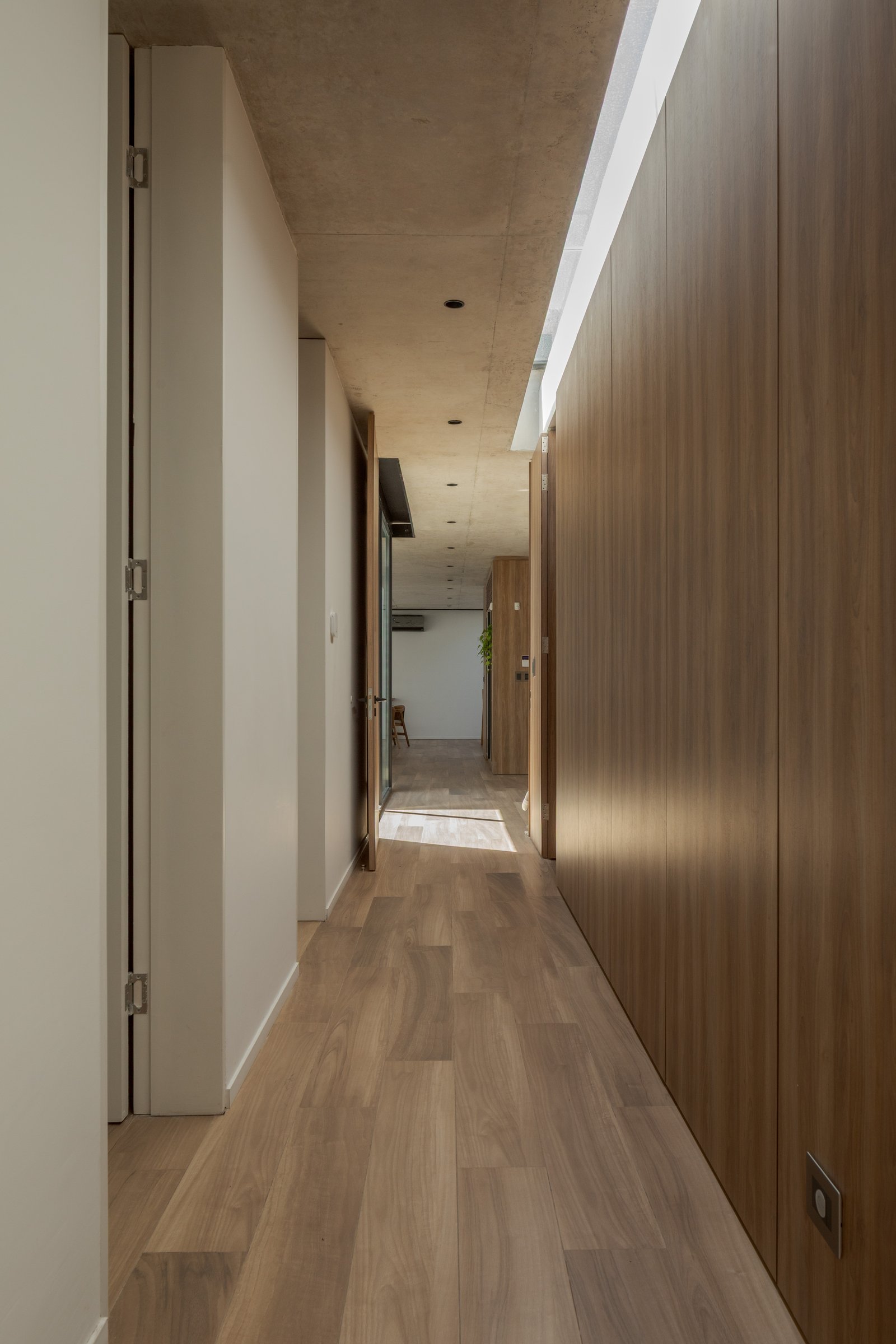 Pasillo moderno con revestimiento de madera y techo de hormigón — proyecto Casa PLANALTO, por Grupo CRBN, en Av. Pres. Perón 10298