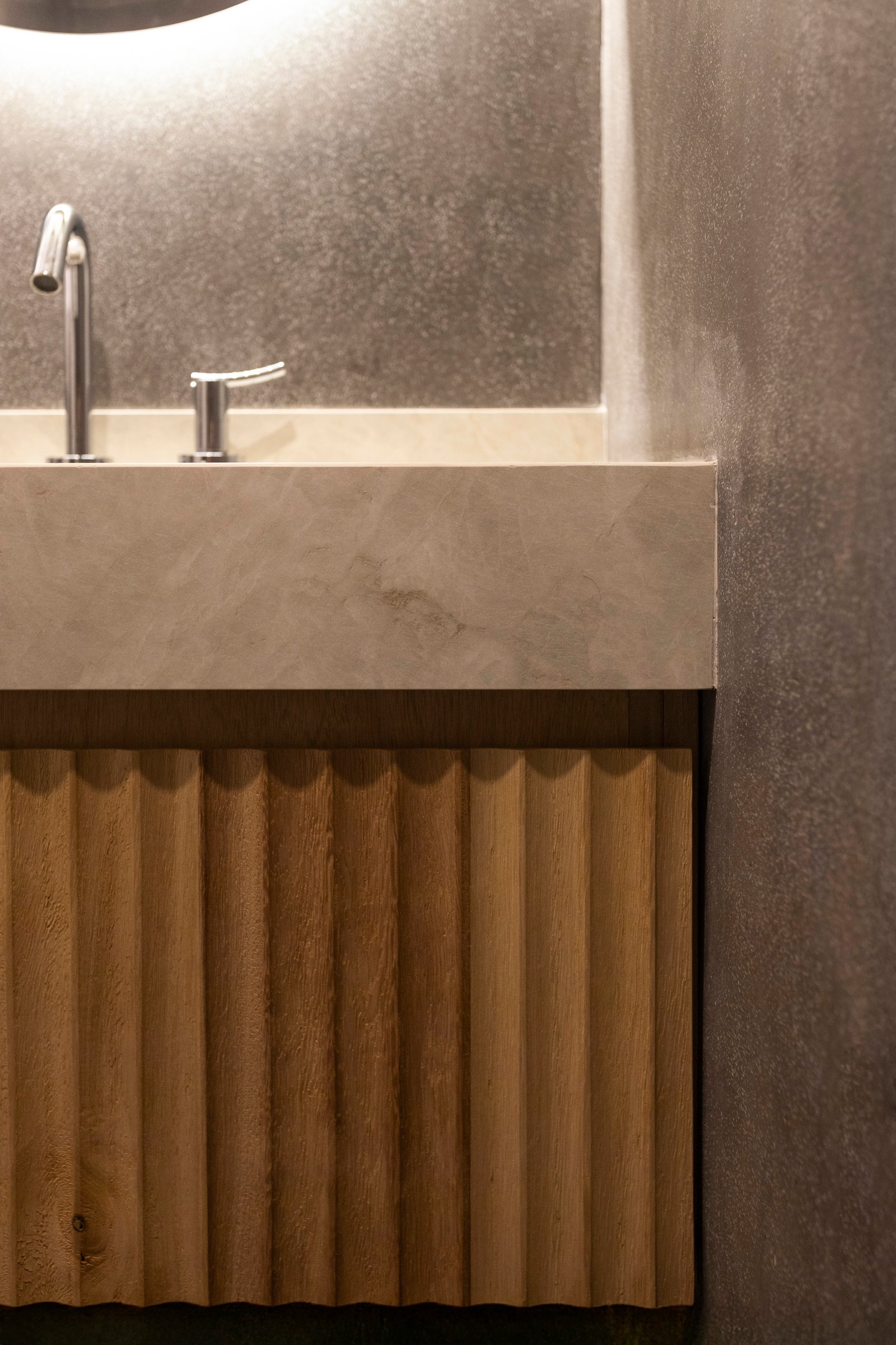 Baño moderno con mesada de microcemento gris y mueble de madera acanalada — proyecto MONASTERIO, por La Nave Arq., en Vicente López
