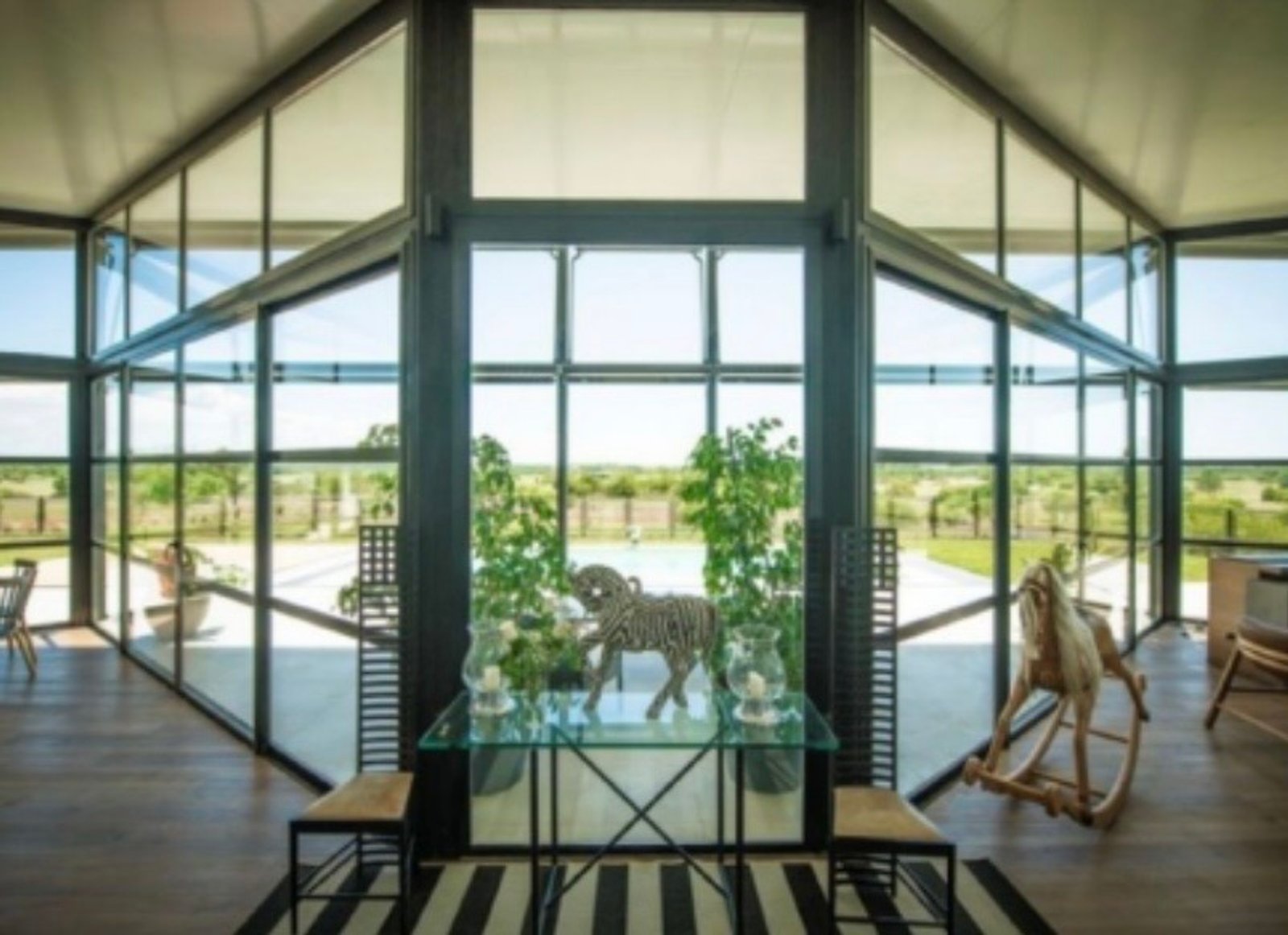 Living moderno con vistas al campo y ventanales de piso a techo — proyecto B House (OMA), por ACH Architecture, en Colonia Department