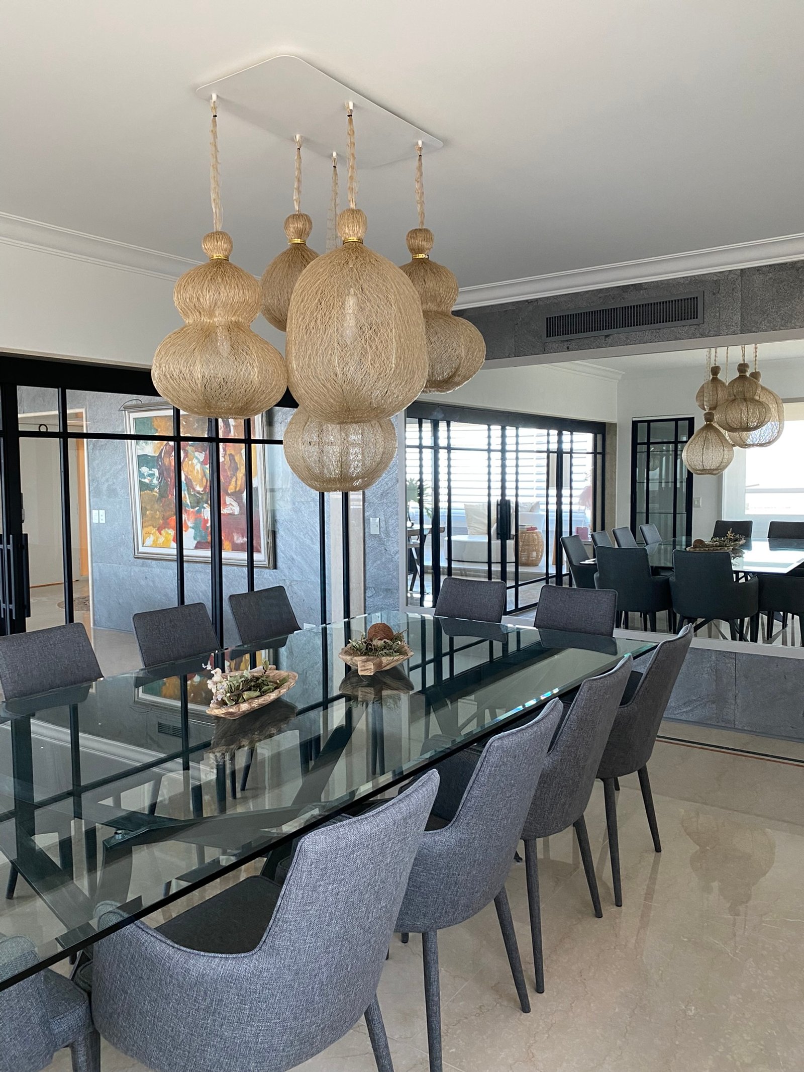 Comedor moderno con lámpara colgante tejida y mesa de cristal — proyecto Libertador I, por MDBK Arquitectura, en Palermo