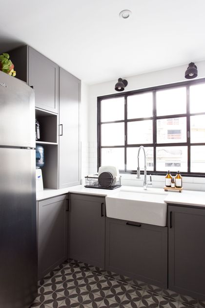 Cocina moderna con muebles negros, mesada blanca y ventanal industrial — proyecto Obra Olazábal II, por SYA Arquitectas, en Belgrano