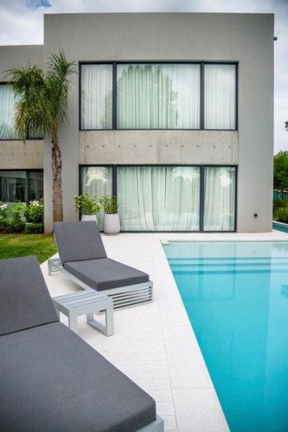 Casa moderna con piscina, fachada de hormigón y grandes ventanales — proyecto trv 427, por Estudio Arq Daniel Tarrio
