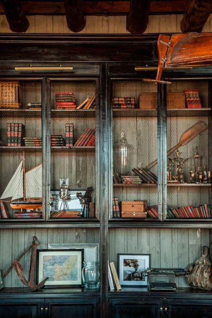 Biblioteca de estilo industrial con vitrinas, libros antiguos y objetos decorativos — proyecto El Sum, por El Naudir