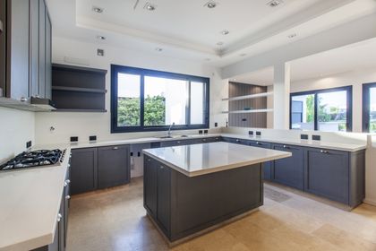 Cocina moderna con isla central, muebles grises y ventanales azules — proyecto El Golf 137 - Nordelta, por Build a Home Arquitectura, en B1624 Tigre