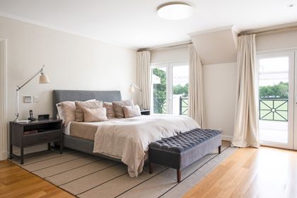 Dormitorio moderno con cama gris, piso de madera y vistas al jardín — proyecto Casa Tortugas , por Estudio Du , en Tortugas Country Club