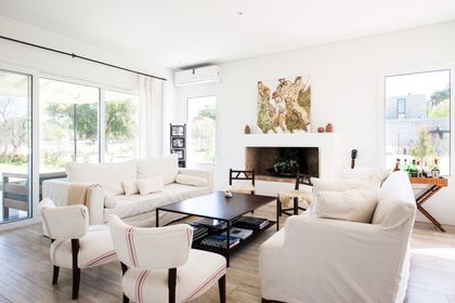 Living moderno con ventanales, sofá blanco y chimenea integrada — proyecto Miradores , por ATO Arquitectos, en Miradores de la Bahia (Bahia Grande Nord