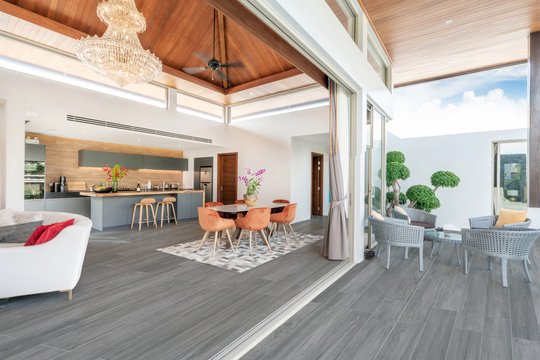 Amplio living comedor moderno con isla de cocina y gran araña de cristal — proyecto 20x120, por Cerámica Alberdi 