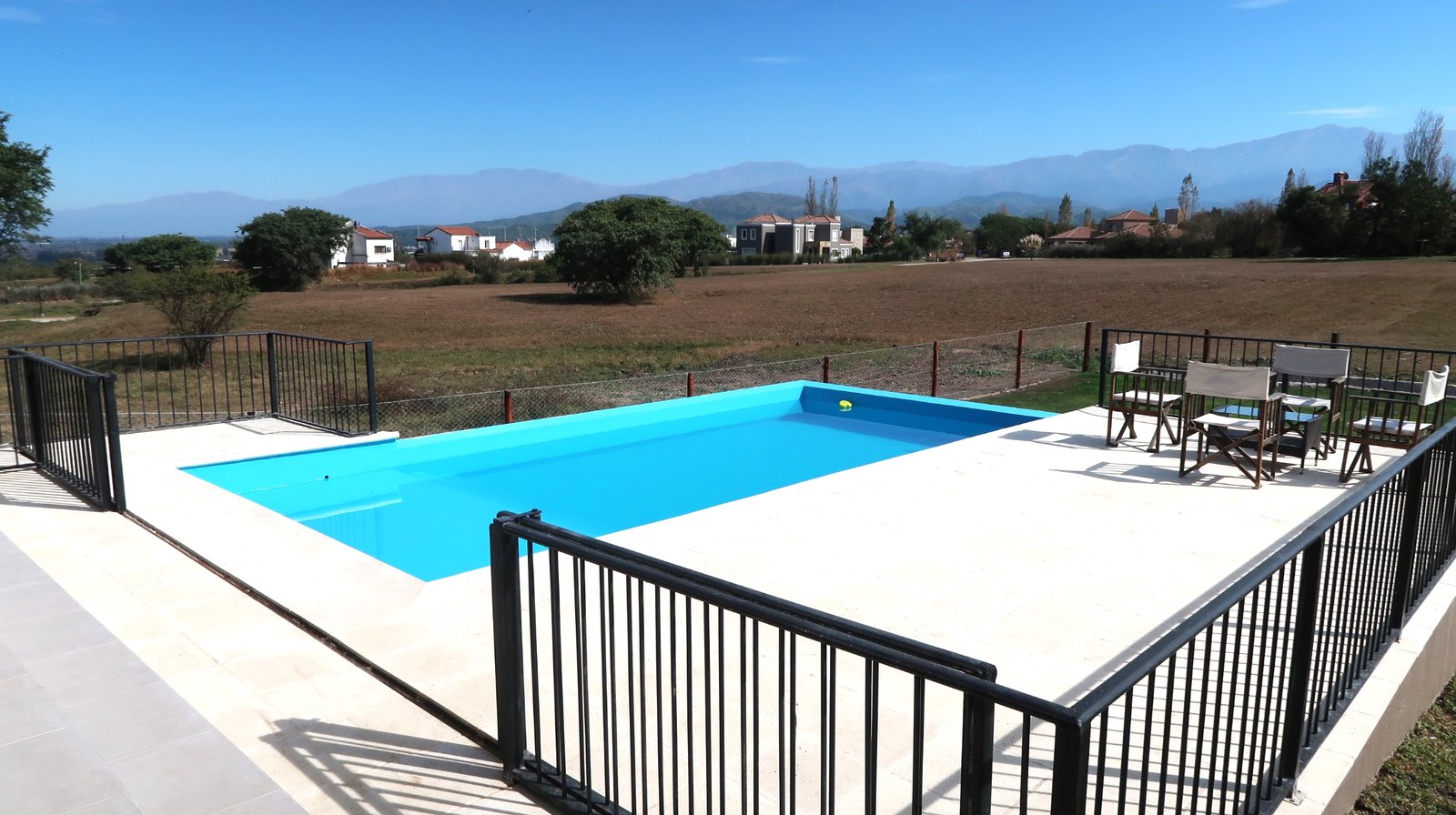 Área de piscina moderna ao ar livre com deck e montanhas ao fundo — projeto Casa La Paz, por Luciana González Anderson, em Salta