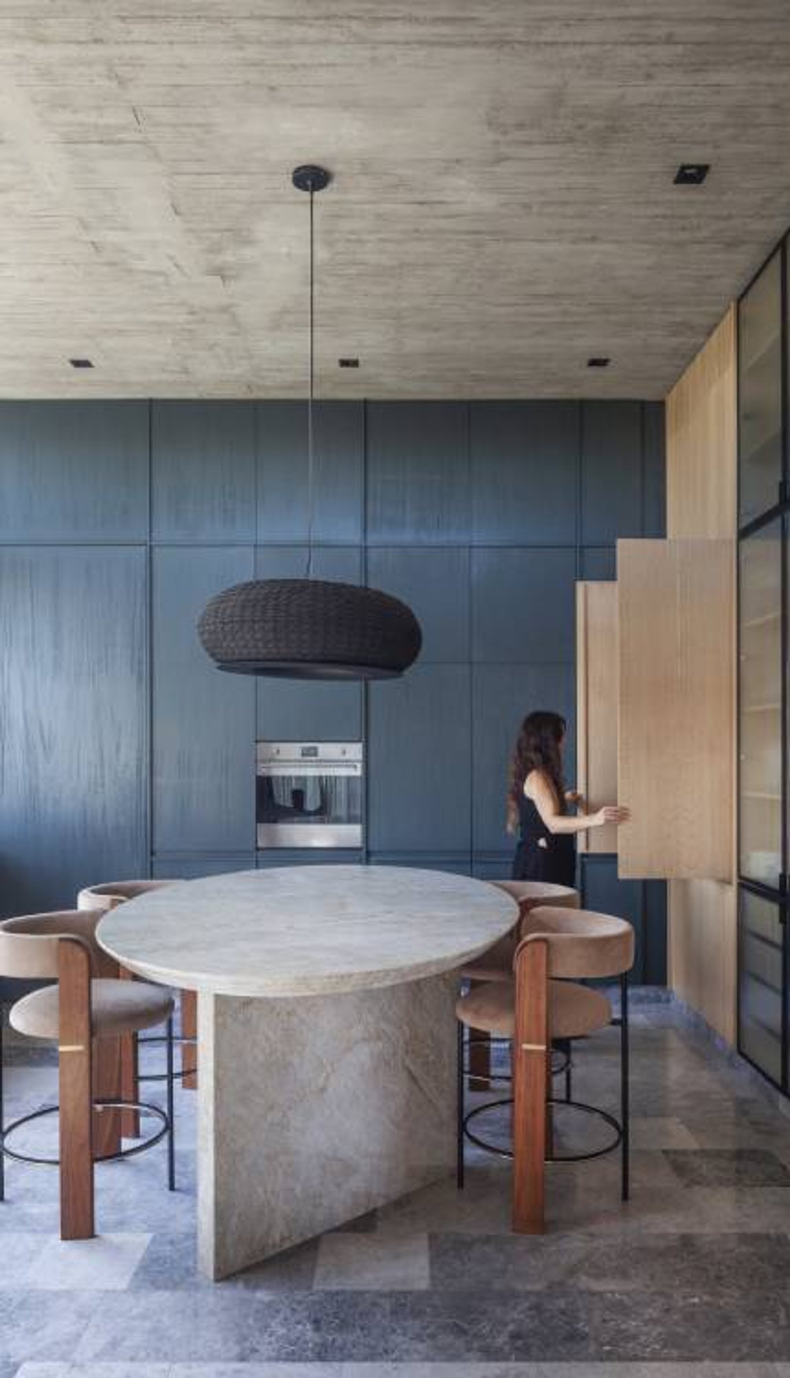 Cocina moderna con isla de piedra y paredes azules texturizadas — proyecto Casa Órbita, por Estudio PK, en Nordelta