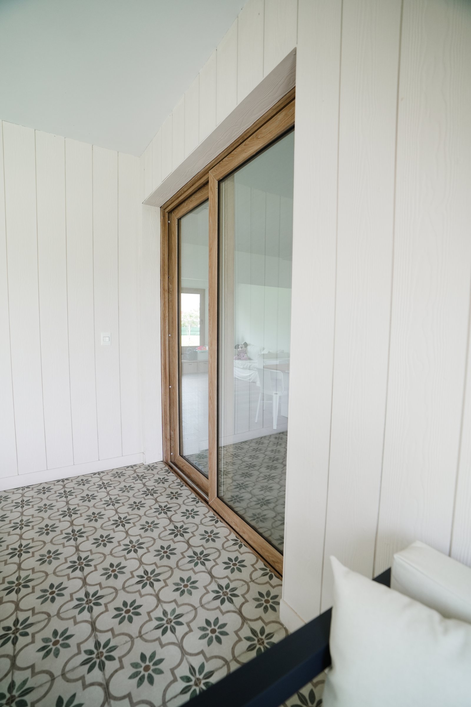 Varanda com piso estampado e porta de correr de vidro — projeto Galeria, por CASA1-TROMEN, em Bella Vista