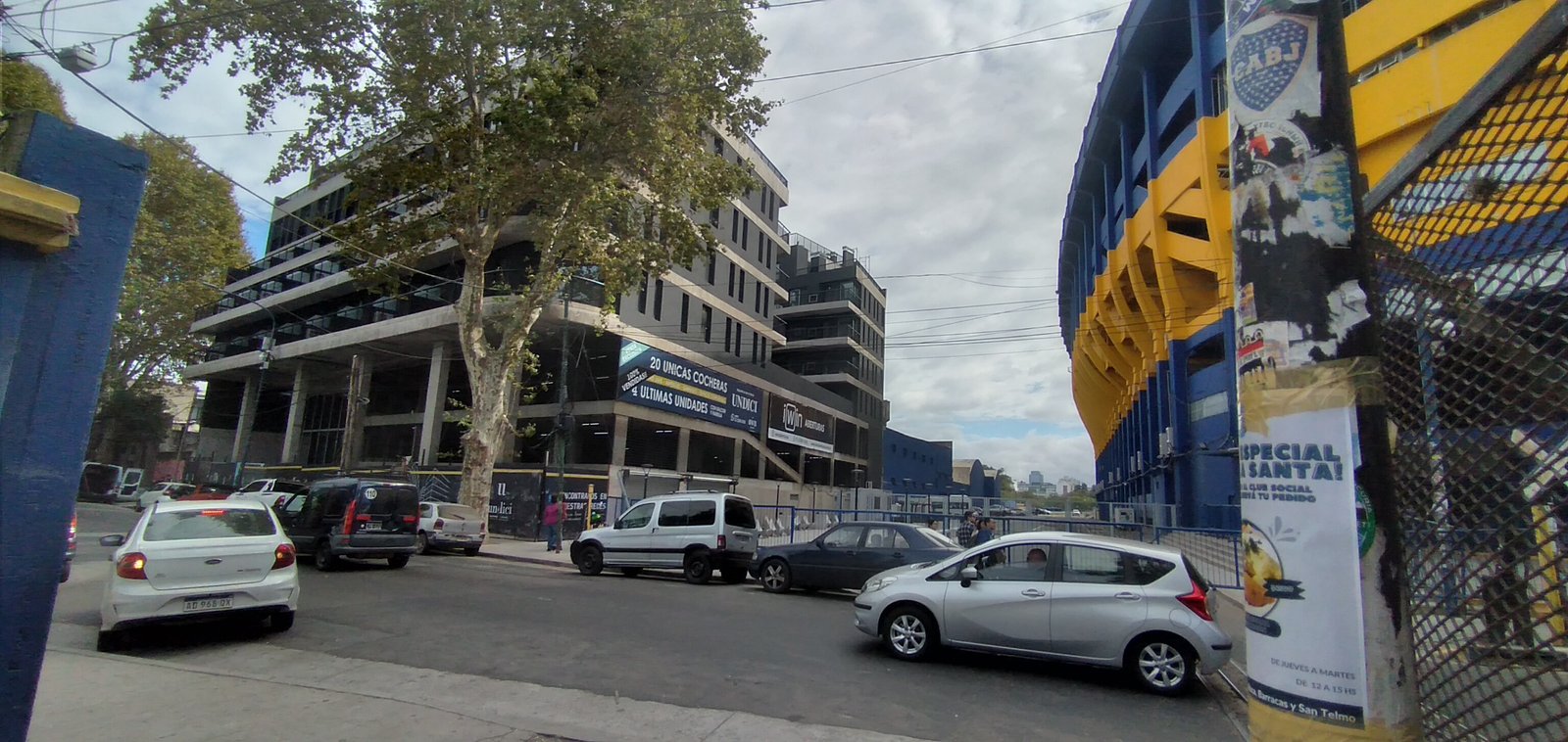 Prédio comercial moderno ao lado de um estádio azul e amarelo — projeto UNDICI - Howard Johnson- La Boca, por COMOTTO - SOMMER  - ARQUITECTOS, em Brandsen 927