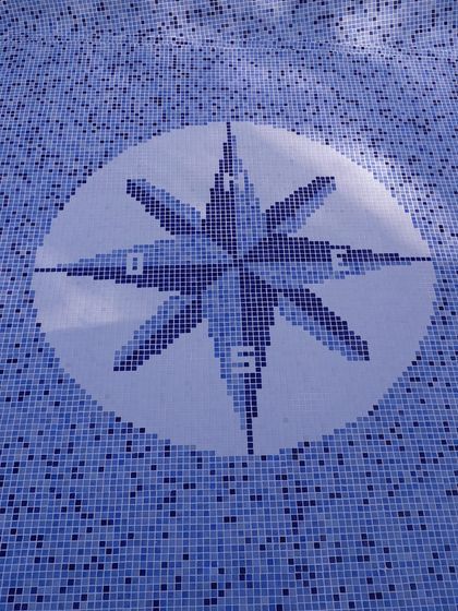 Detalle decorativo de pileta con mosaico azul y diseño geométrico de estrella — proyecto piscina con playa humeda , por Piscinas omar, en General Rodríguez