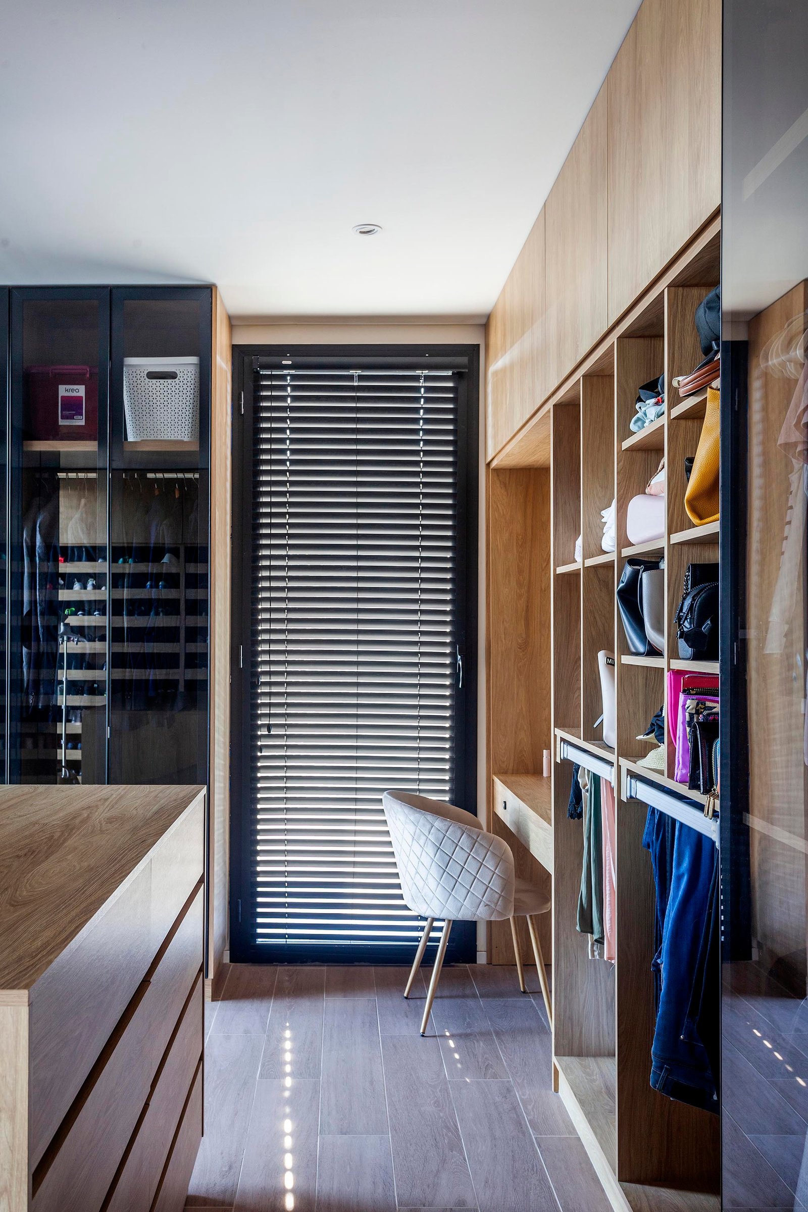 Moderna vestidor con estanterías de madera y silla de diseño — proyecto CASA C313, por A'PRIMA - Arquitectura Sustentable, en Provincia de Buenos Aires