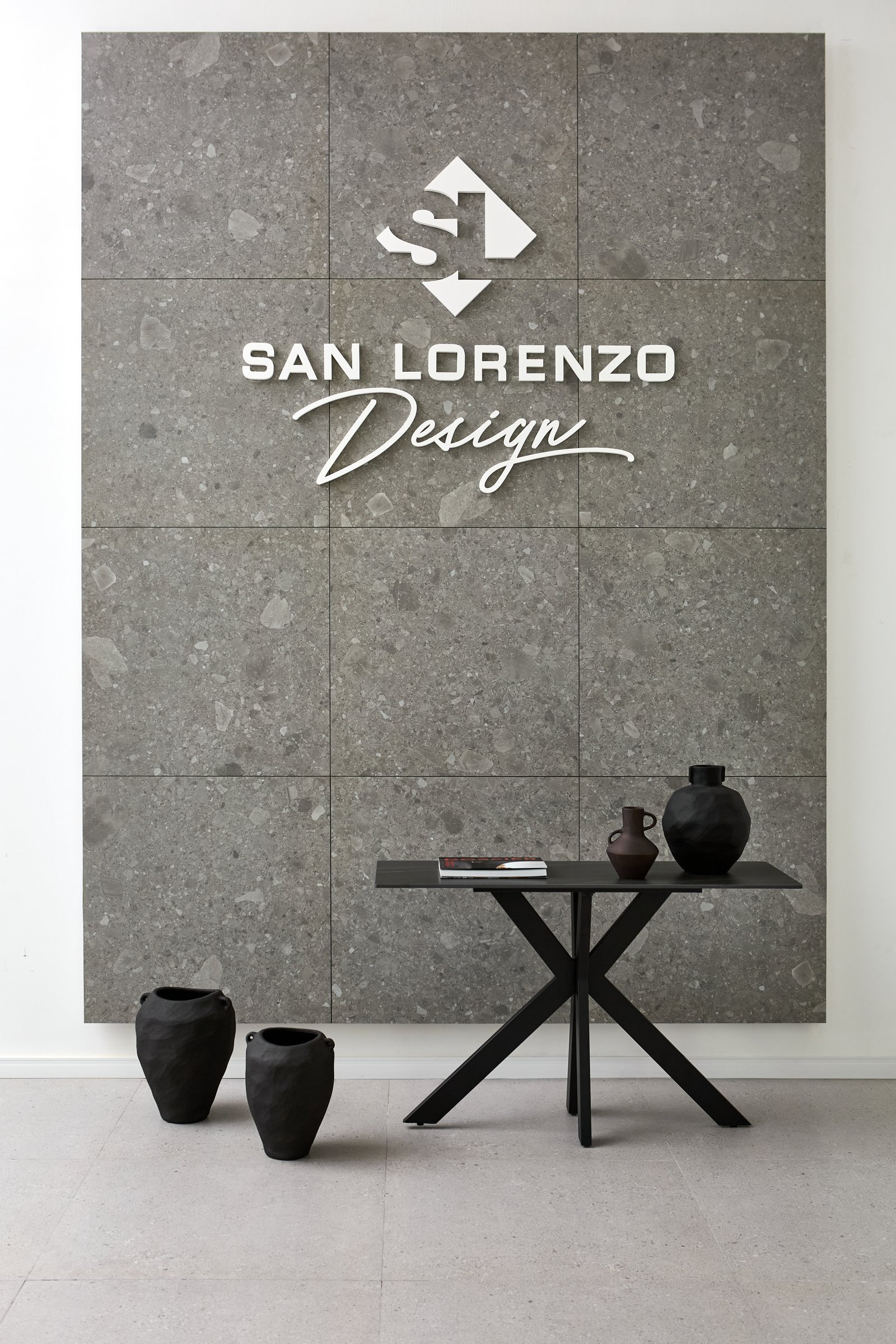 Interior comercial moderno com parede de pedra, logo San Lorenzo Design e mesa geométrica — projeto Showroom, por San Lorenzo Design, em Buenos Aires