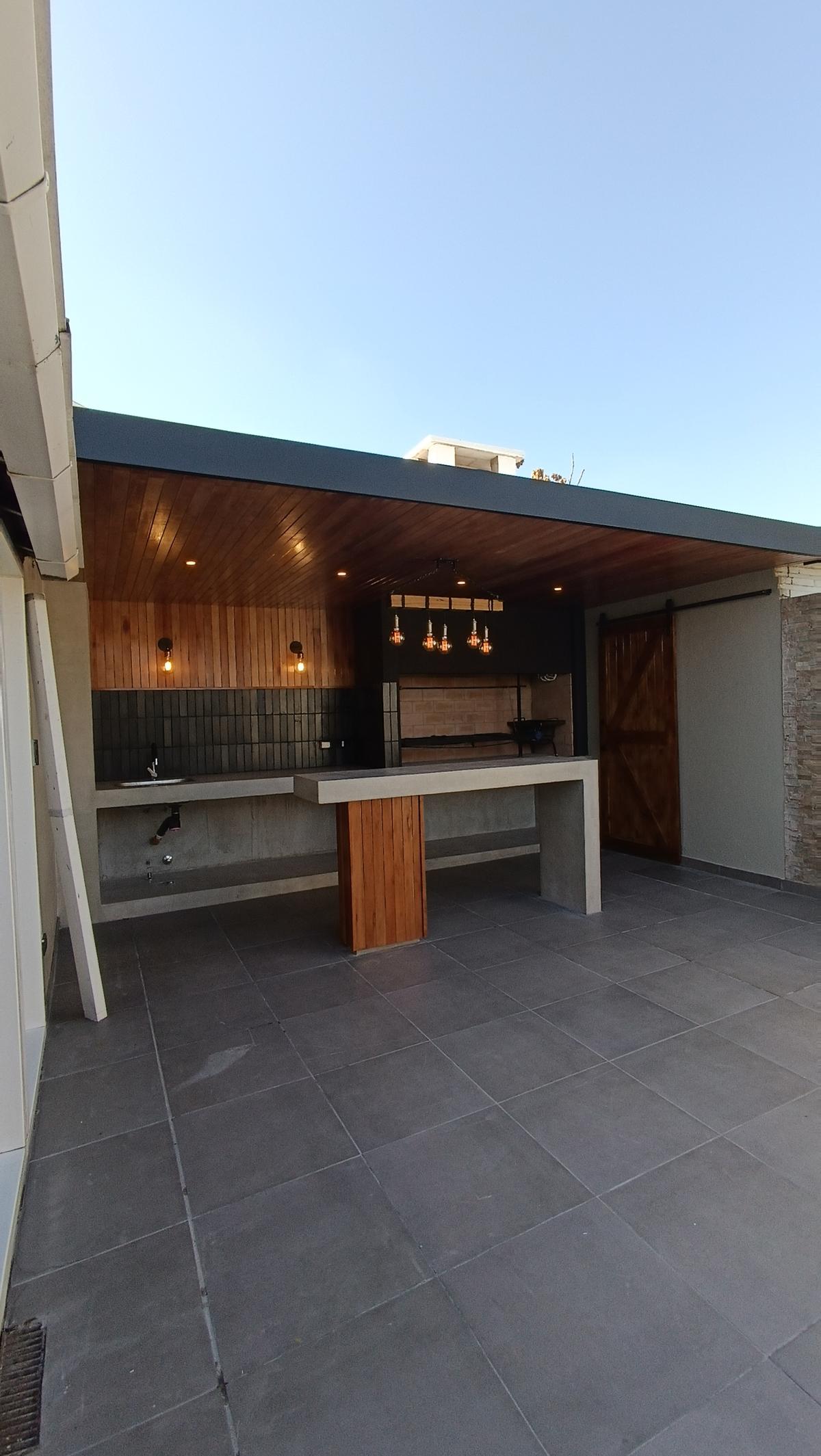Área gourmet moderna com teto de madeira, balcão e churrasqueira — projeto PH LOZANO | Vivienda unifamiliar, por dariorivero.estudio, em Buenos Aires