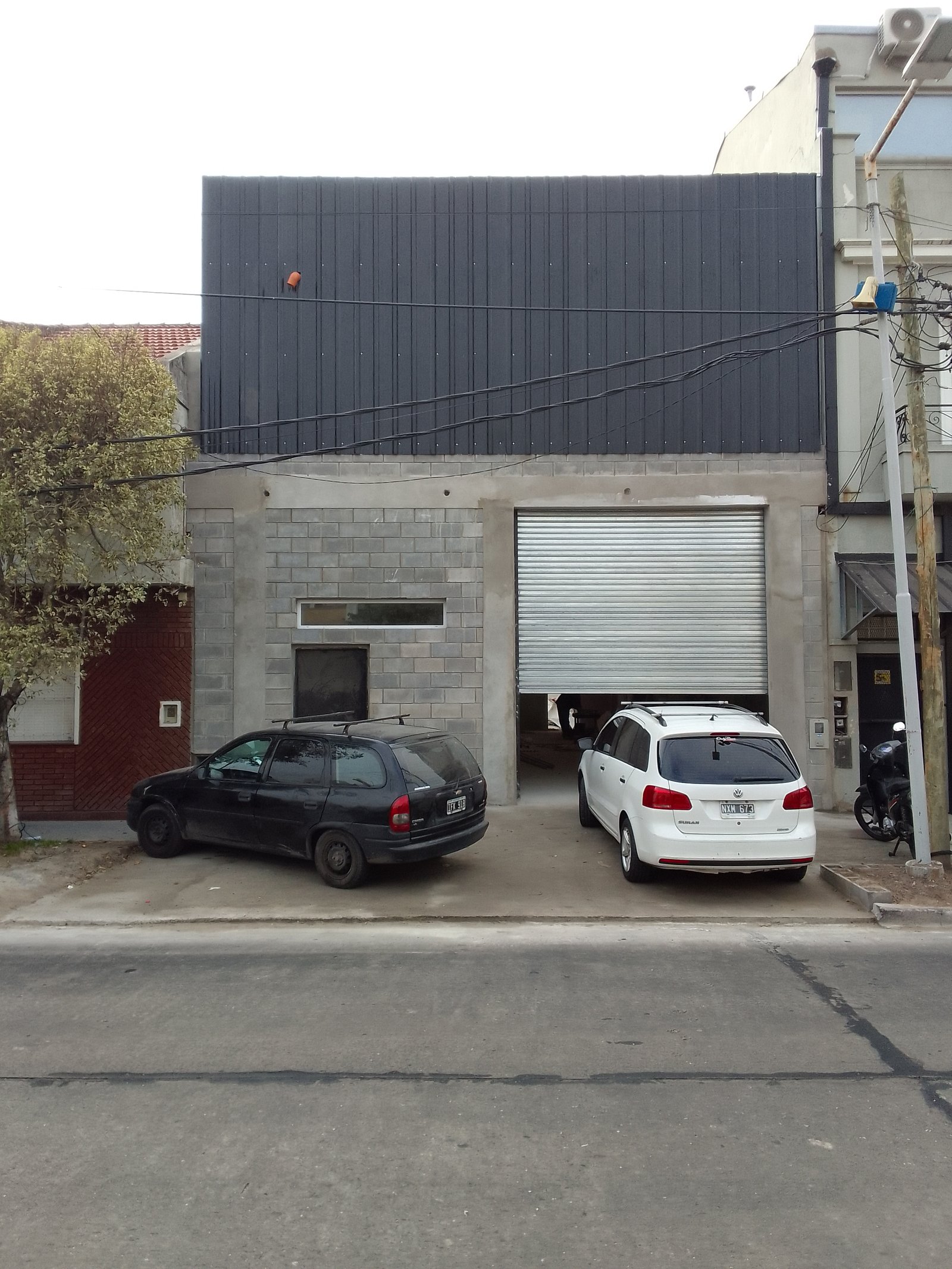 fachada moderna con puerta de garaje enrollable y autos — proyecto Deposito en Avellaneda, por Arquitecto Guido Niccoli, en B1872 Sarandí