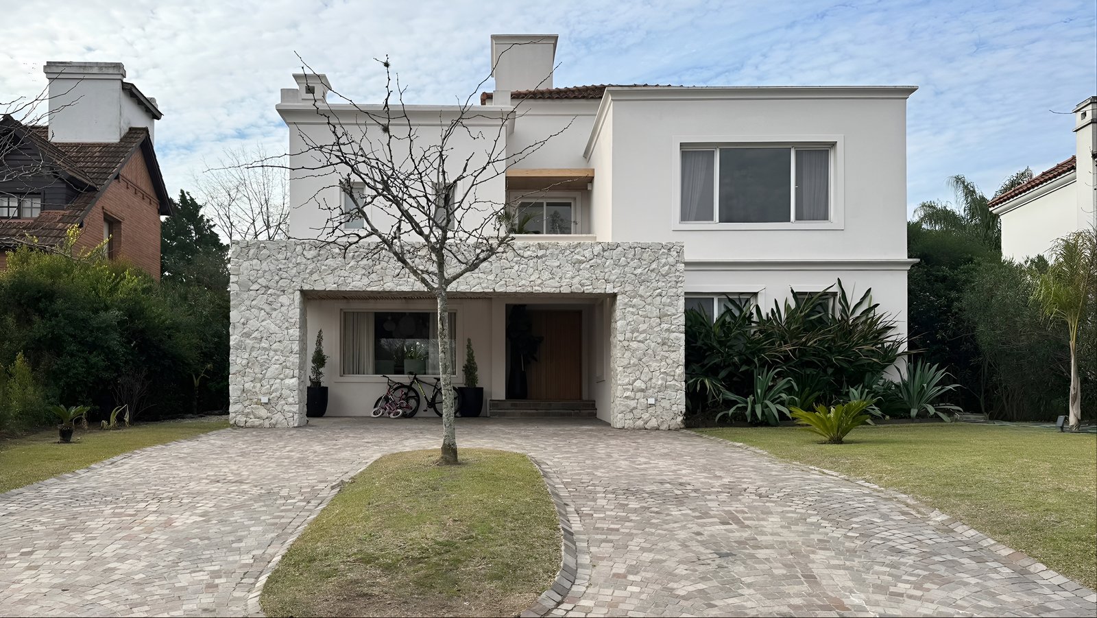 Casa moderna branca com janelas amplas e muro de pedra — projeto Casa CC, por Hermann Arquitectos, em Los Castores