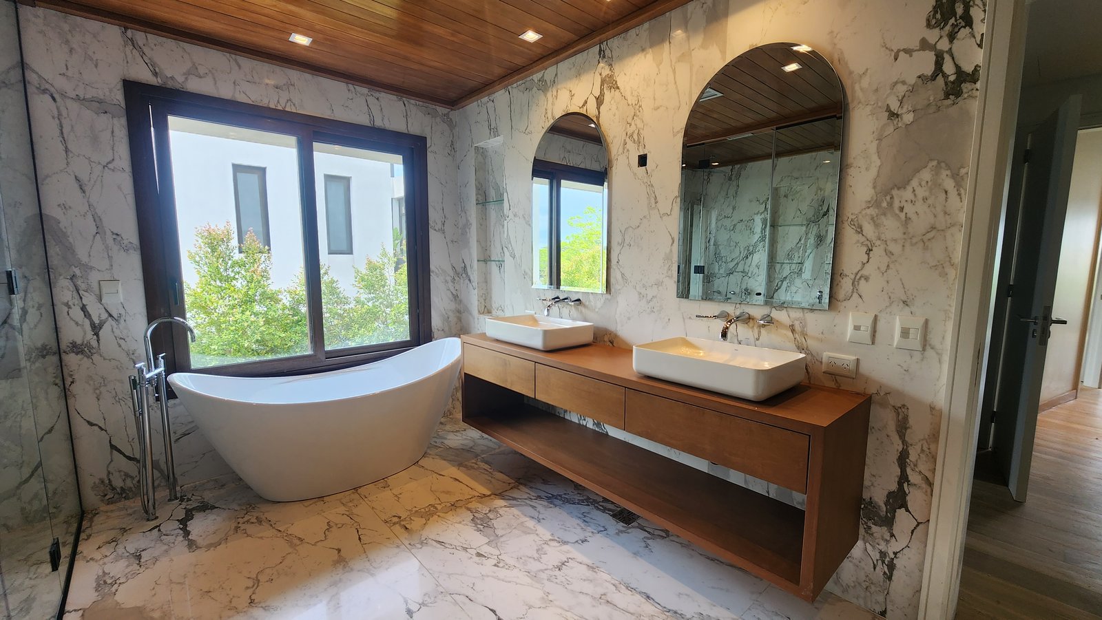 Baño moderno con mármol, madera y bañera exenta — proyecto Reforma El Golf, Nordelta, por Build a Home Arquitectura, en Avenida del Golf s/n