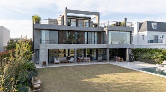 Fachada moderna con amplios ventanales y deck de madera — proyecto Obra Golf Nordelta, por lifecycle, en Tigre