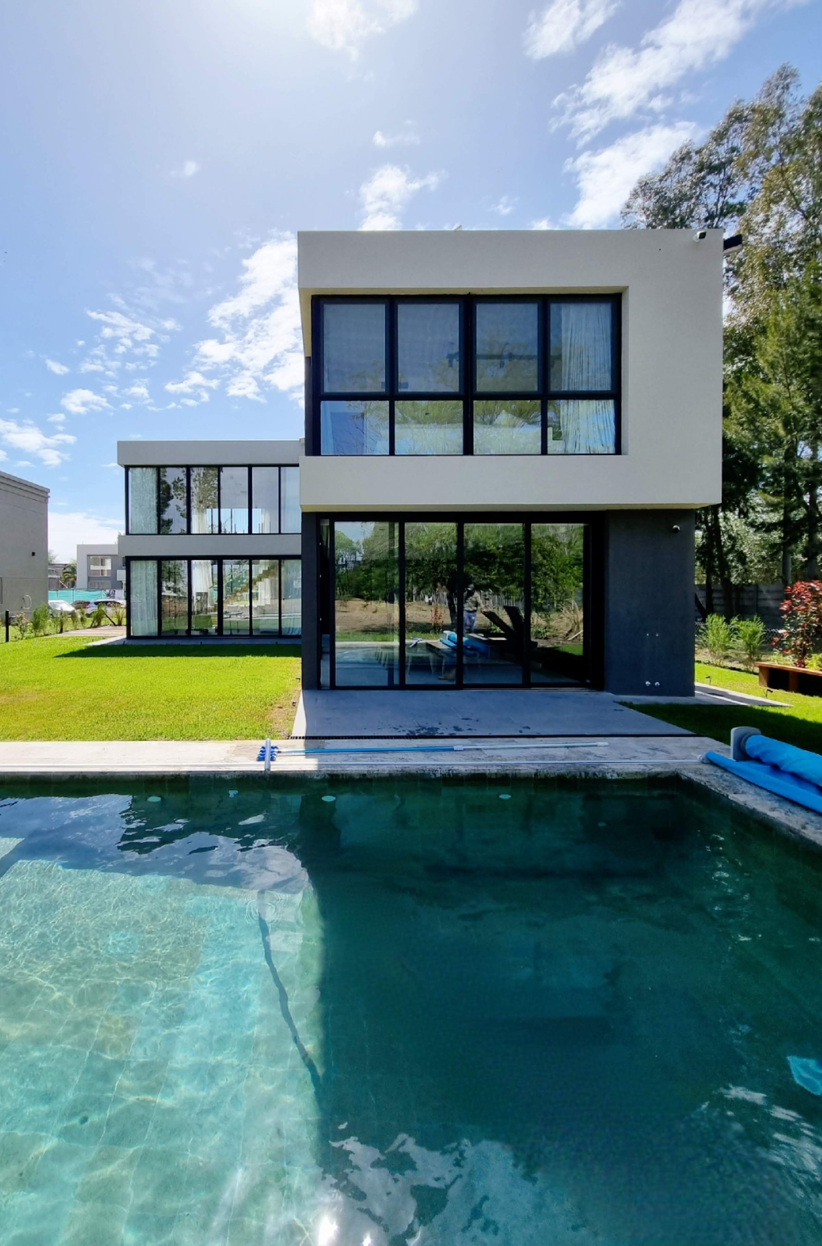 Fachada moderna con piscina y ventanales amplios — proyecto CASA T199, por A'PRIMA - Arquitectura Sustentable, en Los Robles 5901