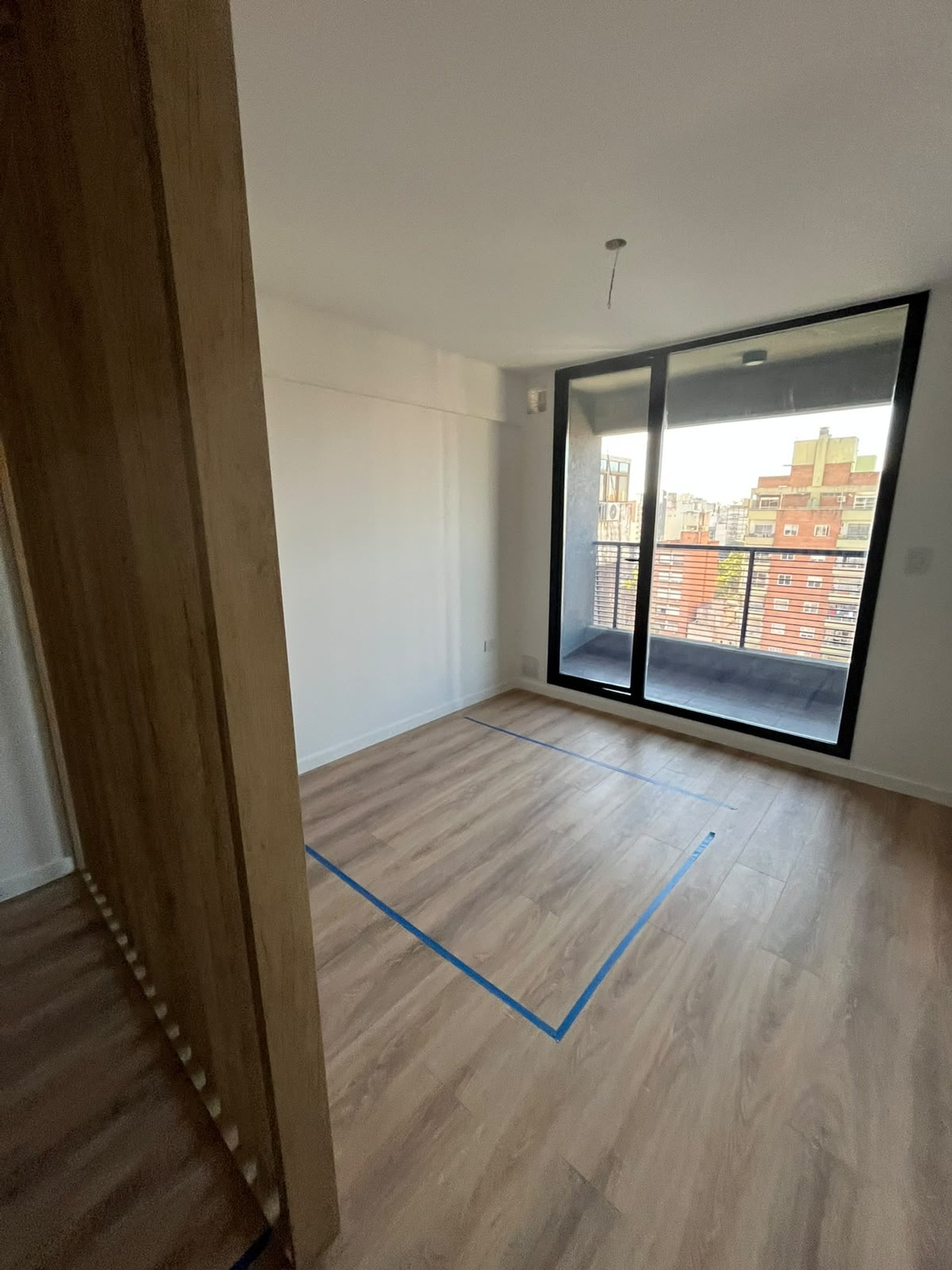 Habitación vacía con piso de madera y gran ventanal — proyecto Proyecto Moreno, por Abelina Estudio, en Rosario