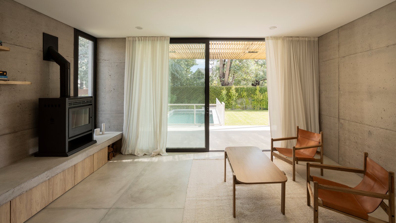 Sala moderna de hormigón con grandes ventanales y piscina — proyecto CASA CC, por Rastro Estudio, en San Isidro