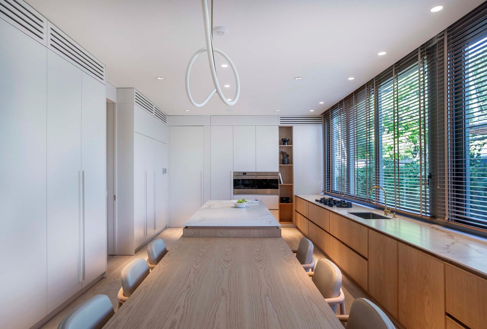 Cocina moderna con isla y mesa larga de comedor, iluminación indirecta — proyecto Casa Magnolia, por Estudio PK, en San Isidro