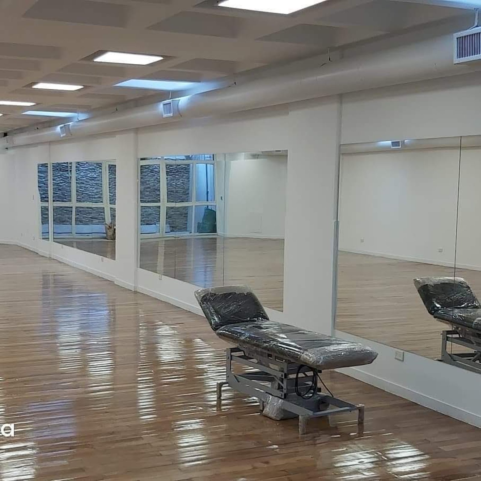 espacio comercial moderno con piso de madera y camilla — proyecto Espejo plata 4mm , por Cristalcenter, en Recoleta