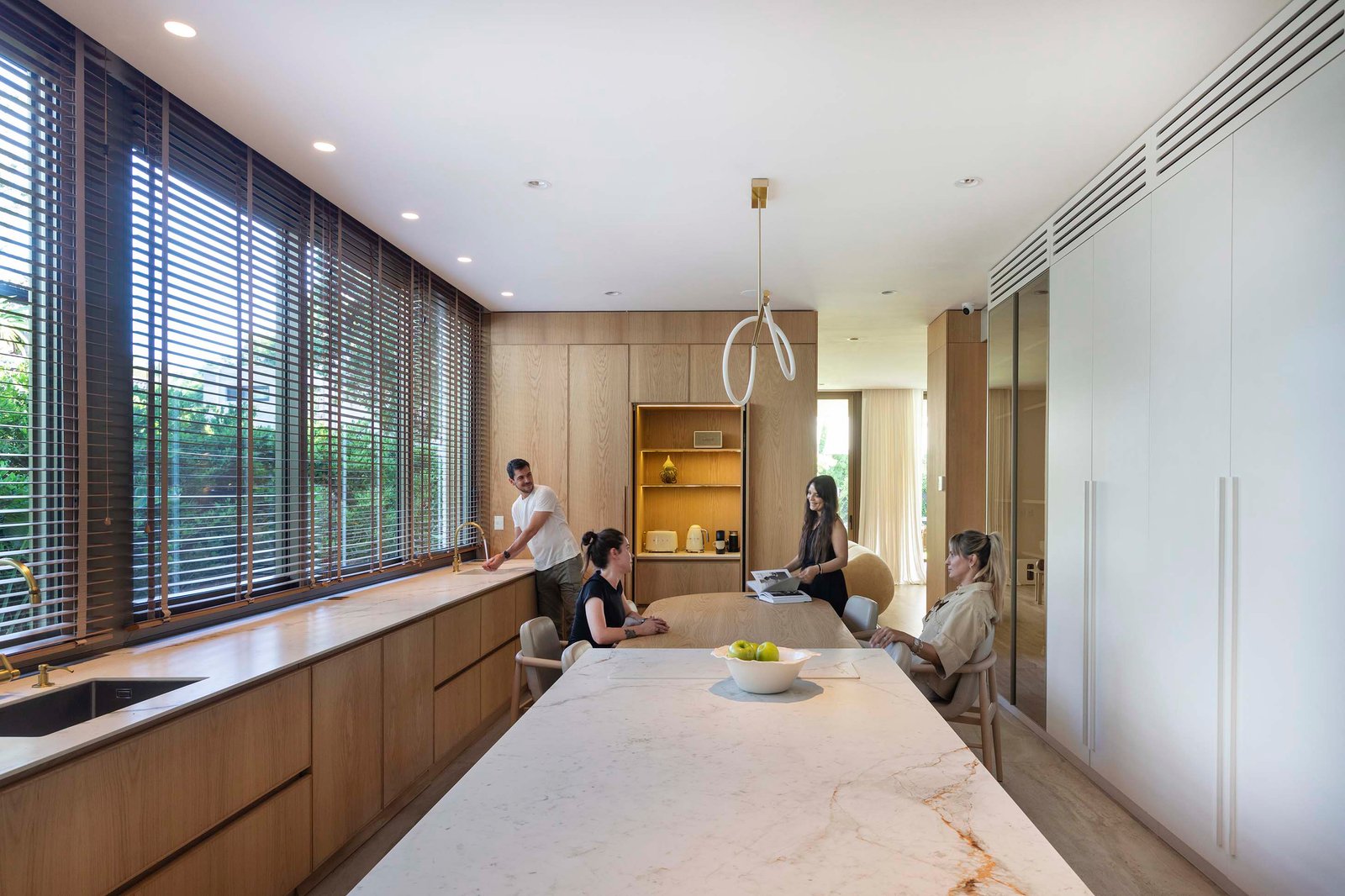 Cocina moderna abierta con isla de mármol y ventanales amplios — proyecto Casa Magnolia, por Estudio PK, en San Isidro