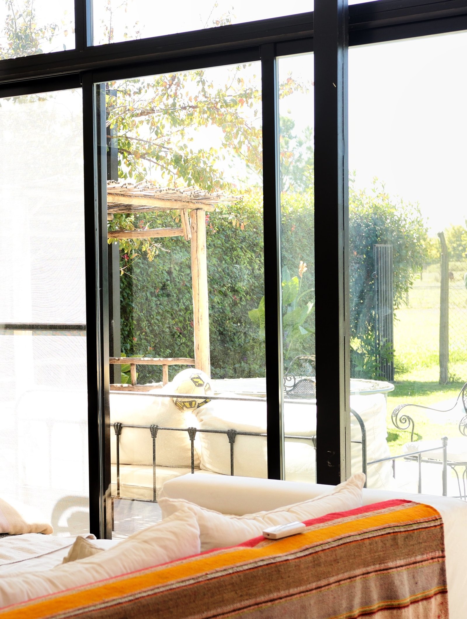 Dormitorio moderno con vista al campo a través de ventanal y pérgola — proyecto FILMS 3M de control Solar, Seguridad y Privacidad, por Grupo Laminar 
