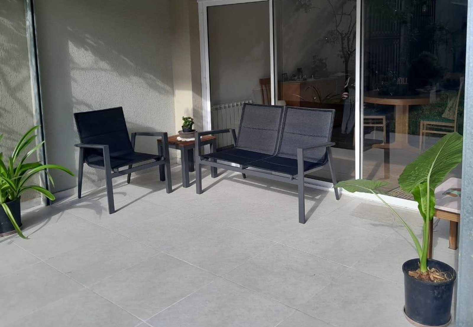 pátio moderno com móveis pretos e plantas — projeto Living Exterior, por Casa Nuñez