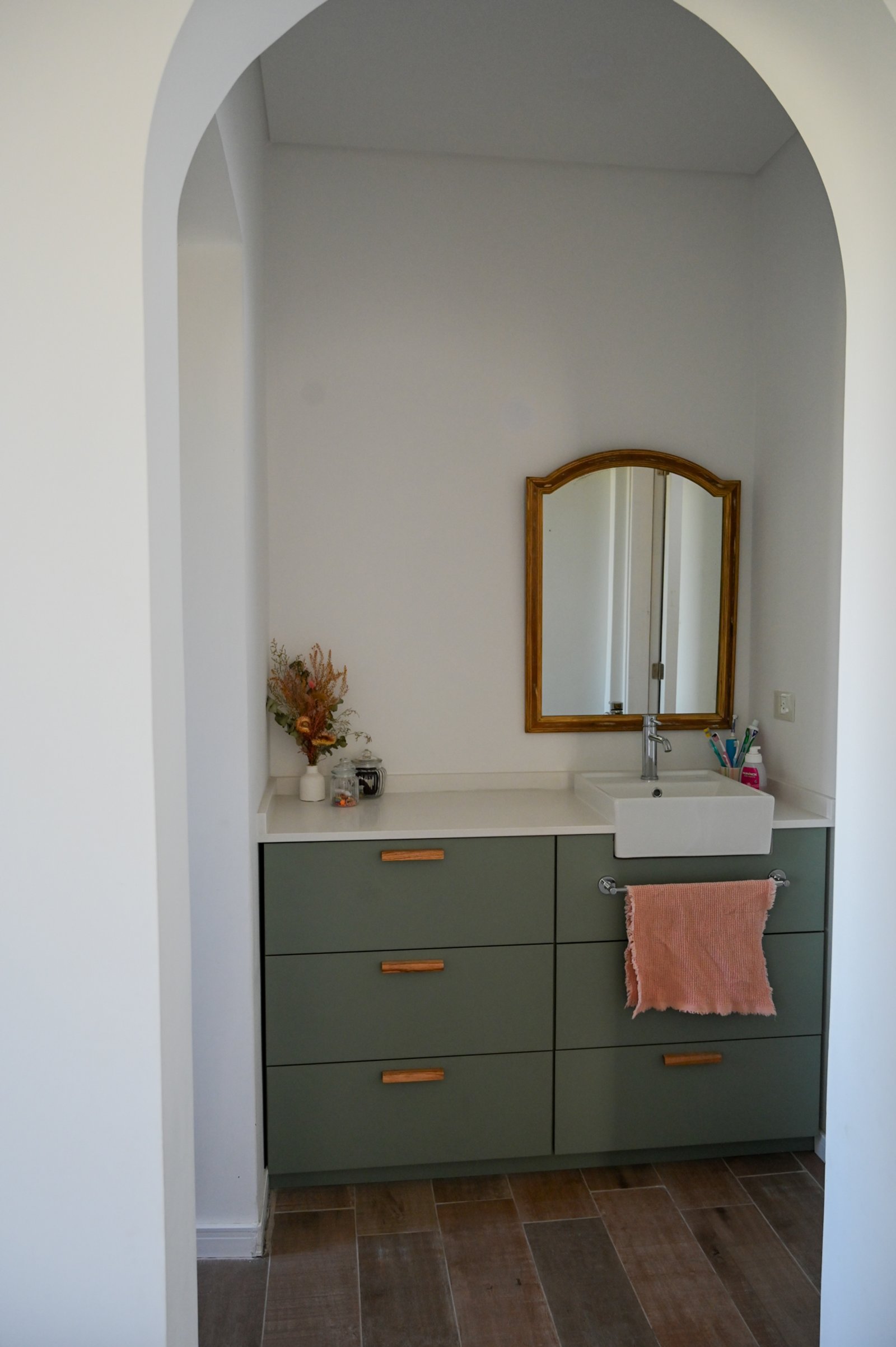 Baño con muebles verdes, mesada de piedra y espejo dorado — proyecto Baños, por CASA1-TROMEN, en Bella Vista