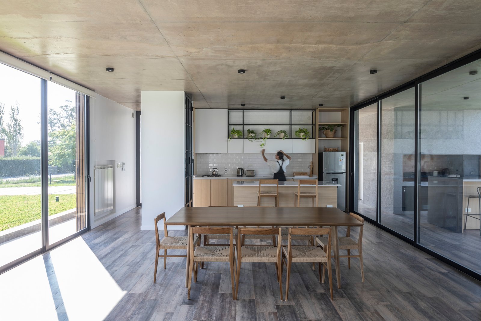 Cozinha-sala de jantar moderna com teto de concreto aparente e janelas amplas — projeto Casa Cruz, por Grupo CRBN, em B2812 Exaltación de la Cruz