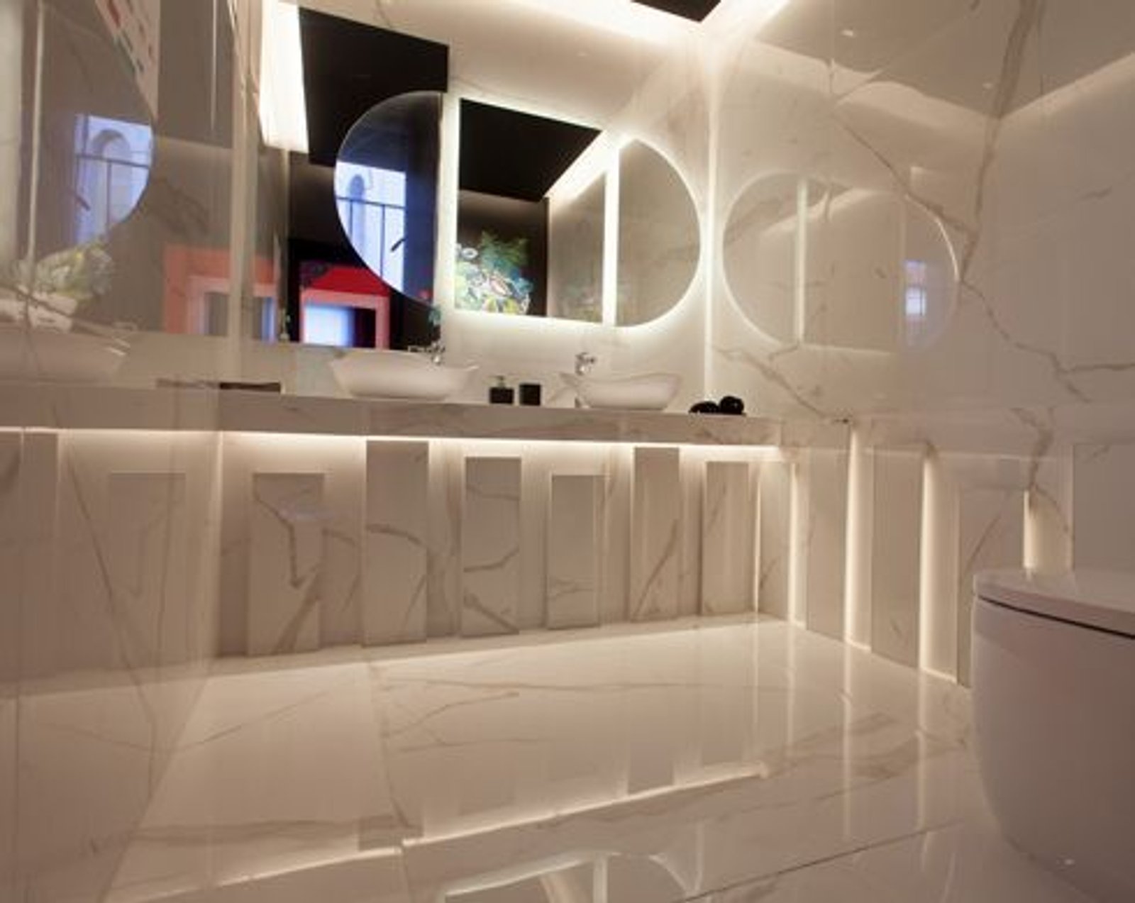 Baño moderno con mármol blanco, iluminación indirecta y espejos redondos — proyecto Casa Foa Retiro 2022, por Vite Porcellanato, en Buenos Aires