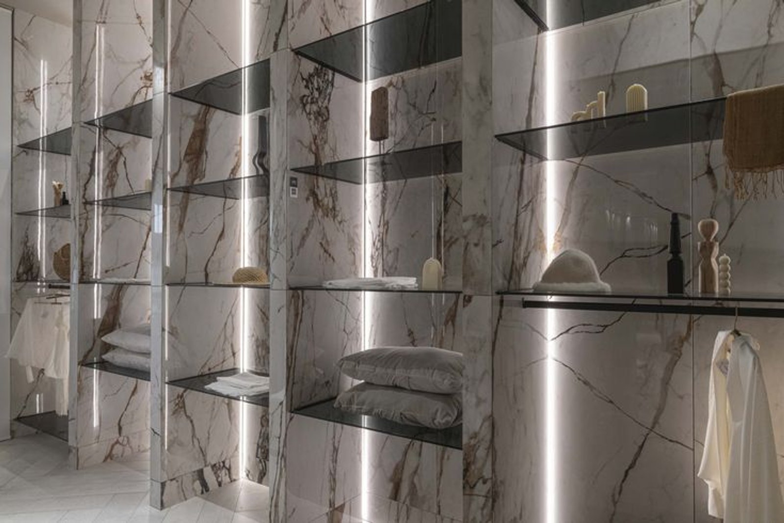 Vestidor moderno con iluminación indirecta y estantes de vidrio — proyecto Casa Foa Parque de la Innovación, por Vite Porcellanato, en Buenos Aires