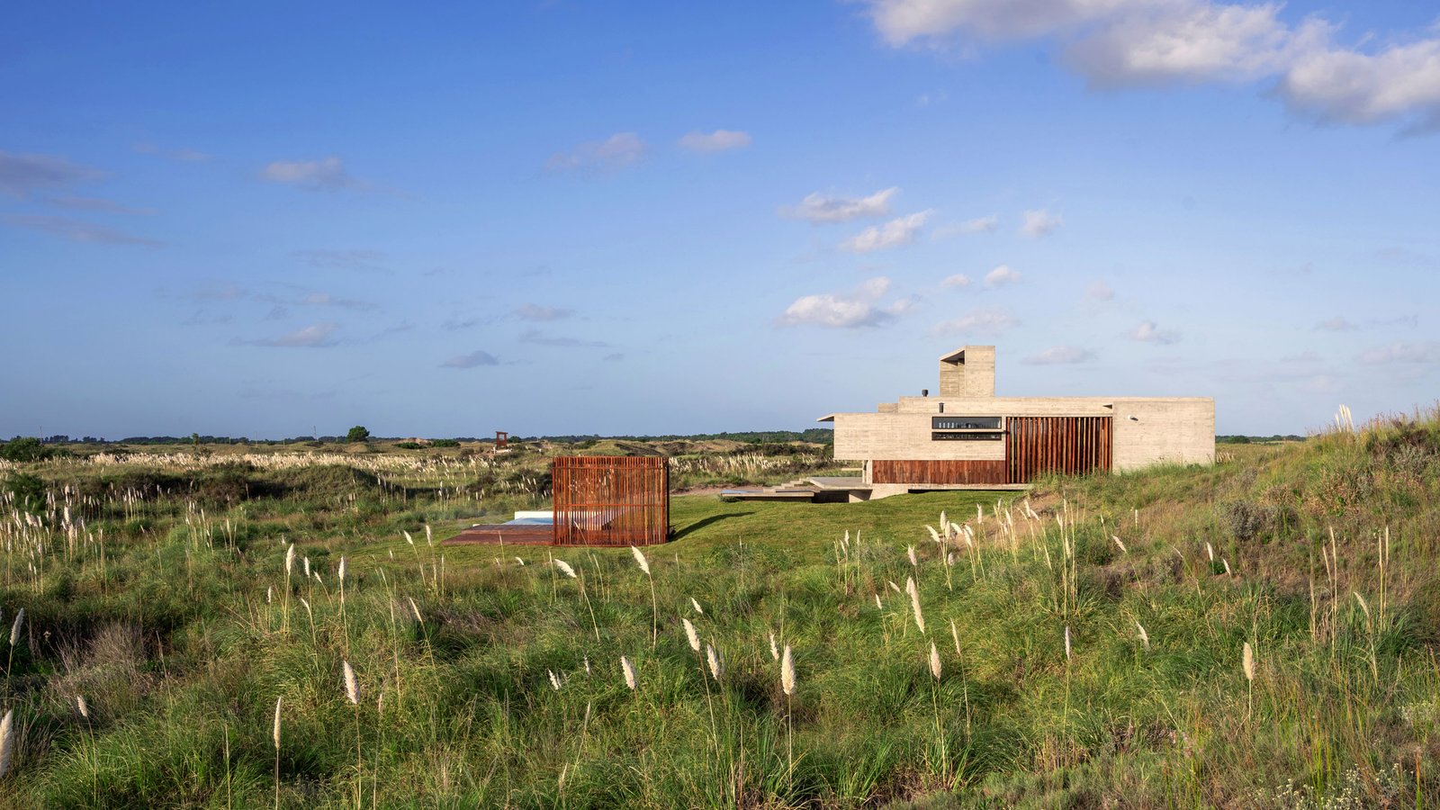 Casa minimalista de concreto em ambiente rural com pergolado — projeto Casa Médanos, por Besonías Almeida arquitectos, em JWRC+MQ