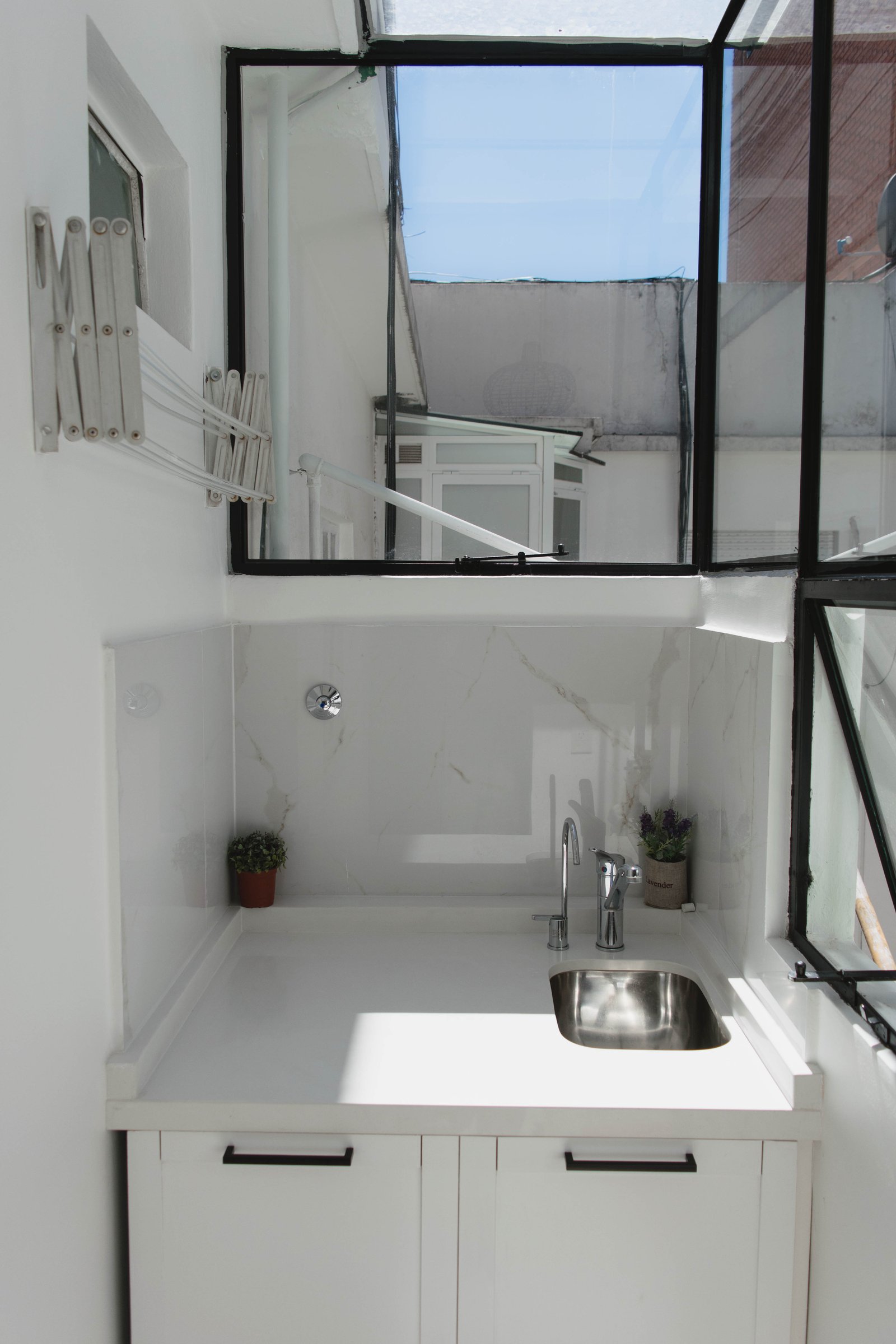 Lavadero moderno con luz cenital y acabados en mármol — proyecto Goyena, por Martina Kleinert, en Caballito