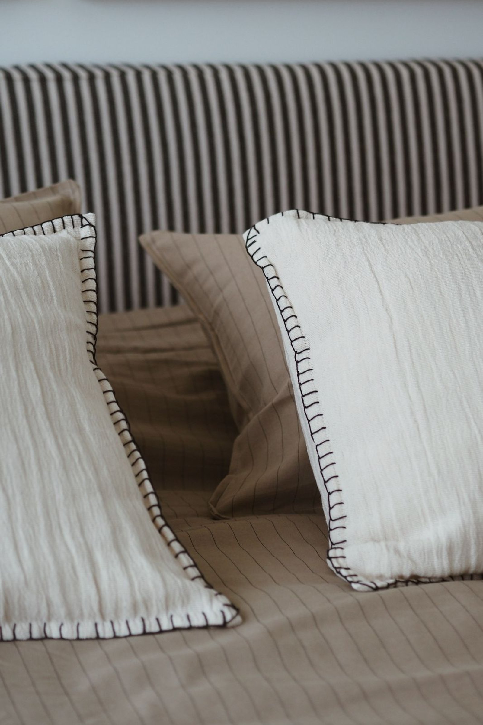 Dormitorio minimalista con almohadones texturizados y ropa de cama a rayas — proyecto RIO, por APATHEIA, en Provincia de Buenos Aires