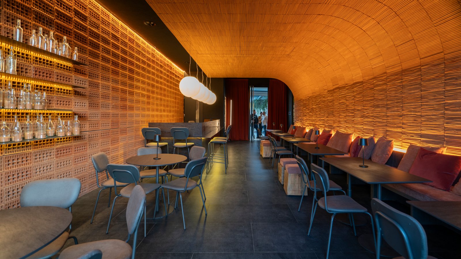 Espacio comercial con techo curvo de madera y paredes de ladrillo visto — proyecto Piedras, por Vite Porcellanato