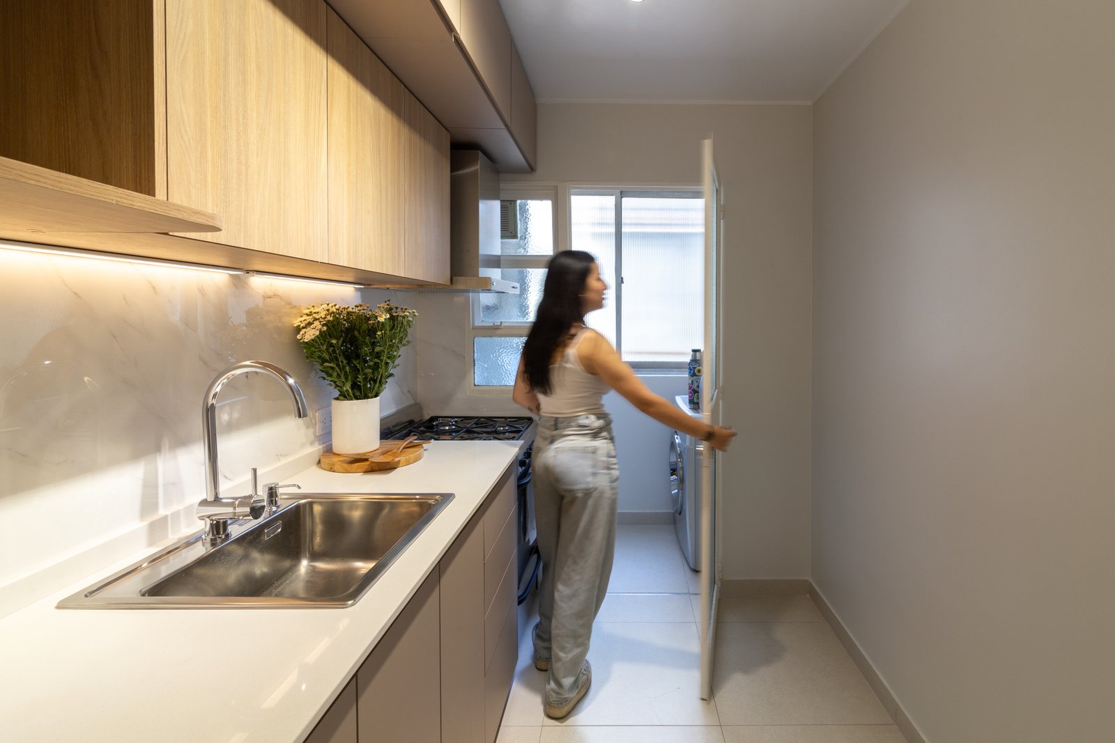 Cozinha moderna com armários de madeira e bancada branca — projeto Gascón, por Martina Kleinert, em Caballito